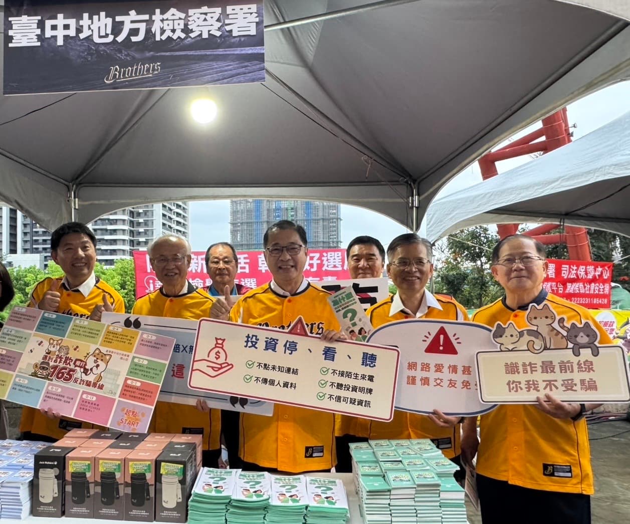 法務部鄭銘謙部長（圖中）到洲際球場宣導打詐反毒反賄選，在反詐詐宣導攤位前以標語提醒民眾打詐重要性。（中信兄弟提供）