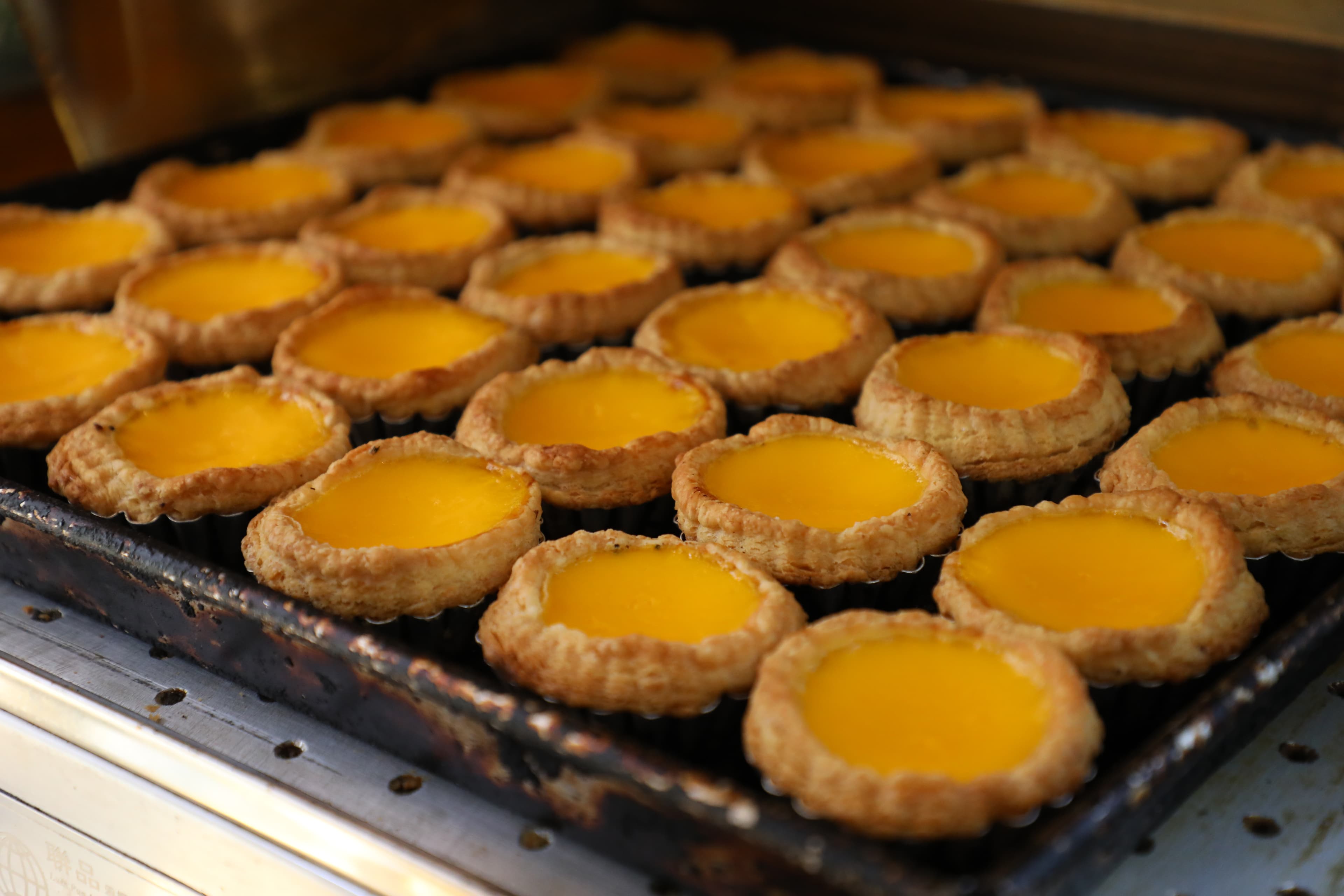 剛出爐的「馳名酥皮蛋塔」香氣四溢，蛋液香濃，酥皮鬆化。（港幣10元／個）
