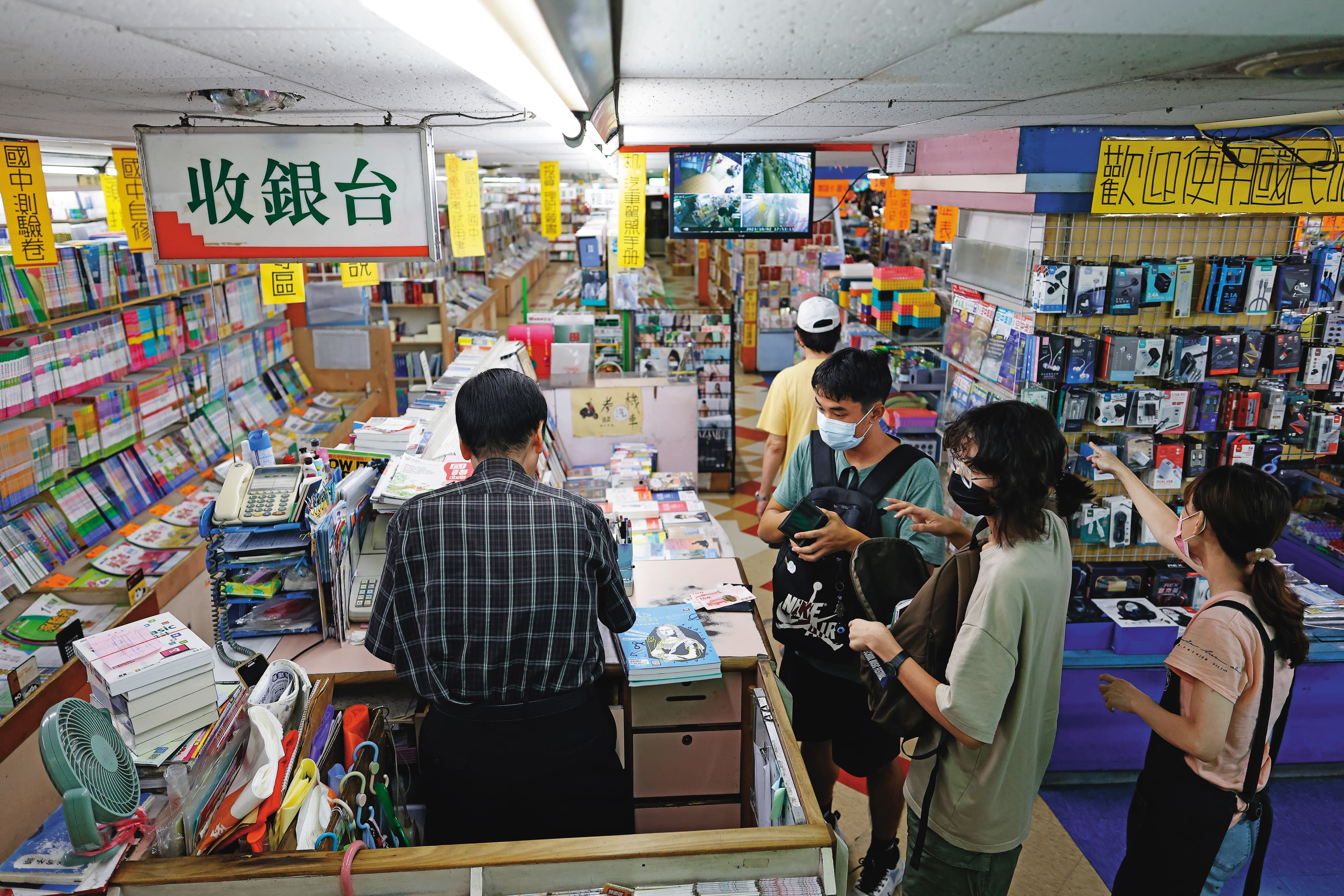 鳳山大書城平日下午客人不斷，幾組是使用文化幣點數放大券的年輕人。老闆張仁飛（左）低調不願上鏡頭。