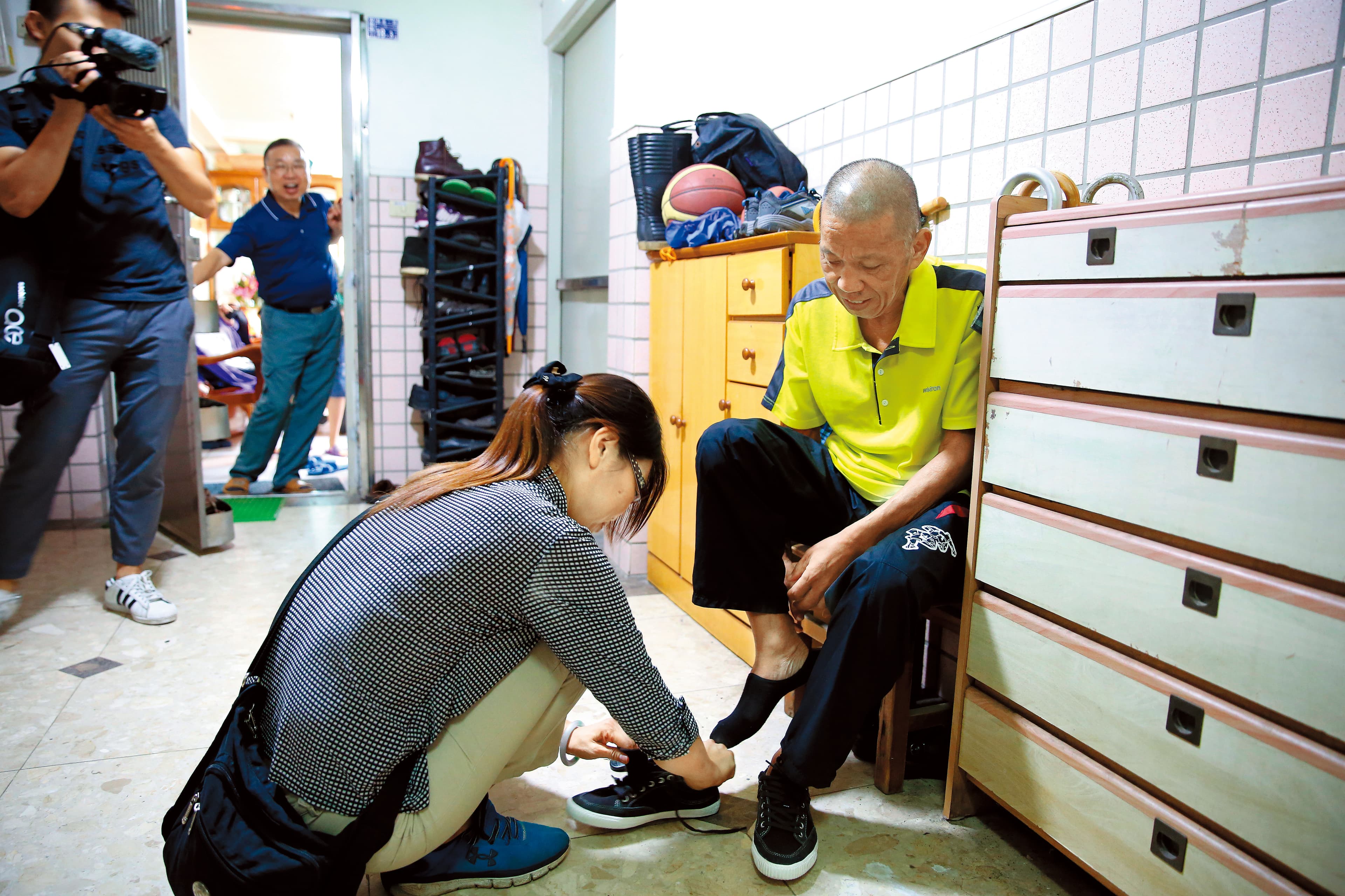 沈妻楊秀慧（左前蹲者）個性堅毅、身材高䠷，但在沈瑞章身旁就成了小女人。看丈夫仍虛弱，自然而然蹲下身為他綁鞋帶。