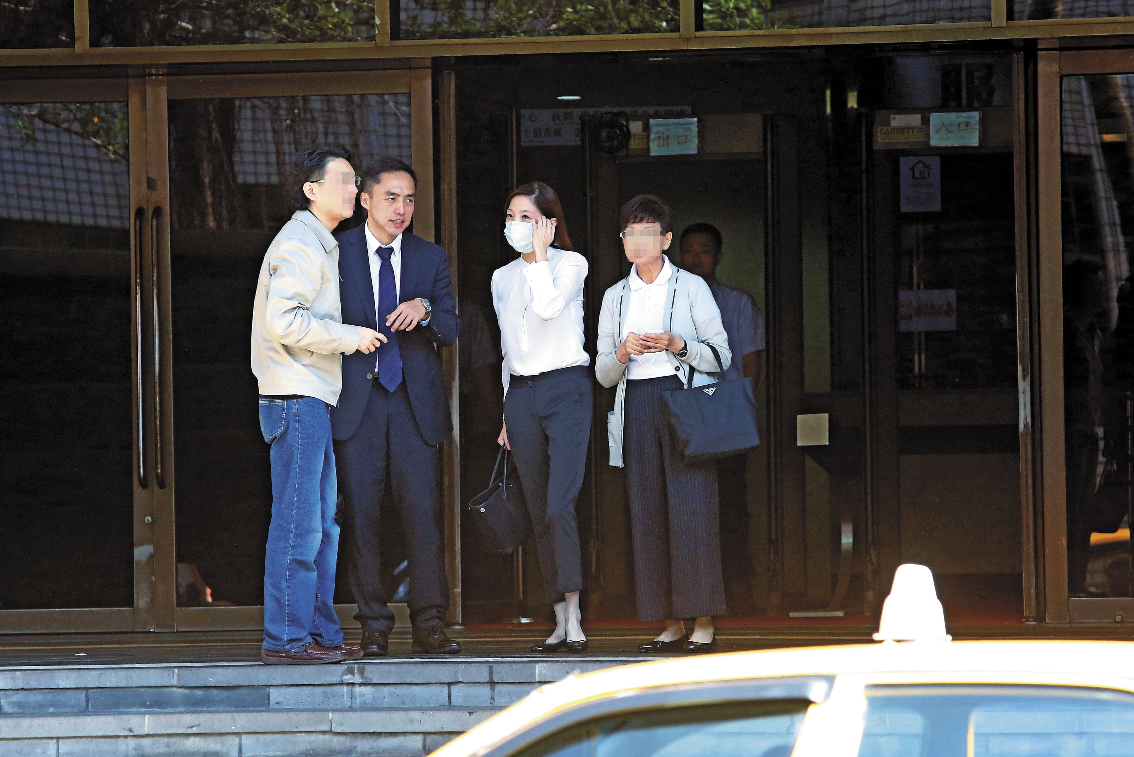 黃閔暄（右2）庭訊後戴上口罩，在律師（左2）及親友陪同下，搭計程車離去。
