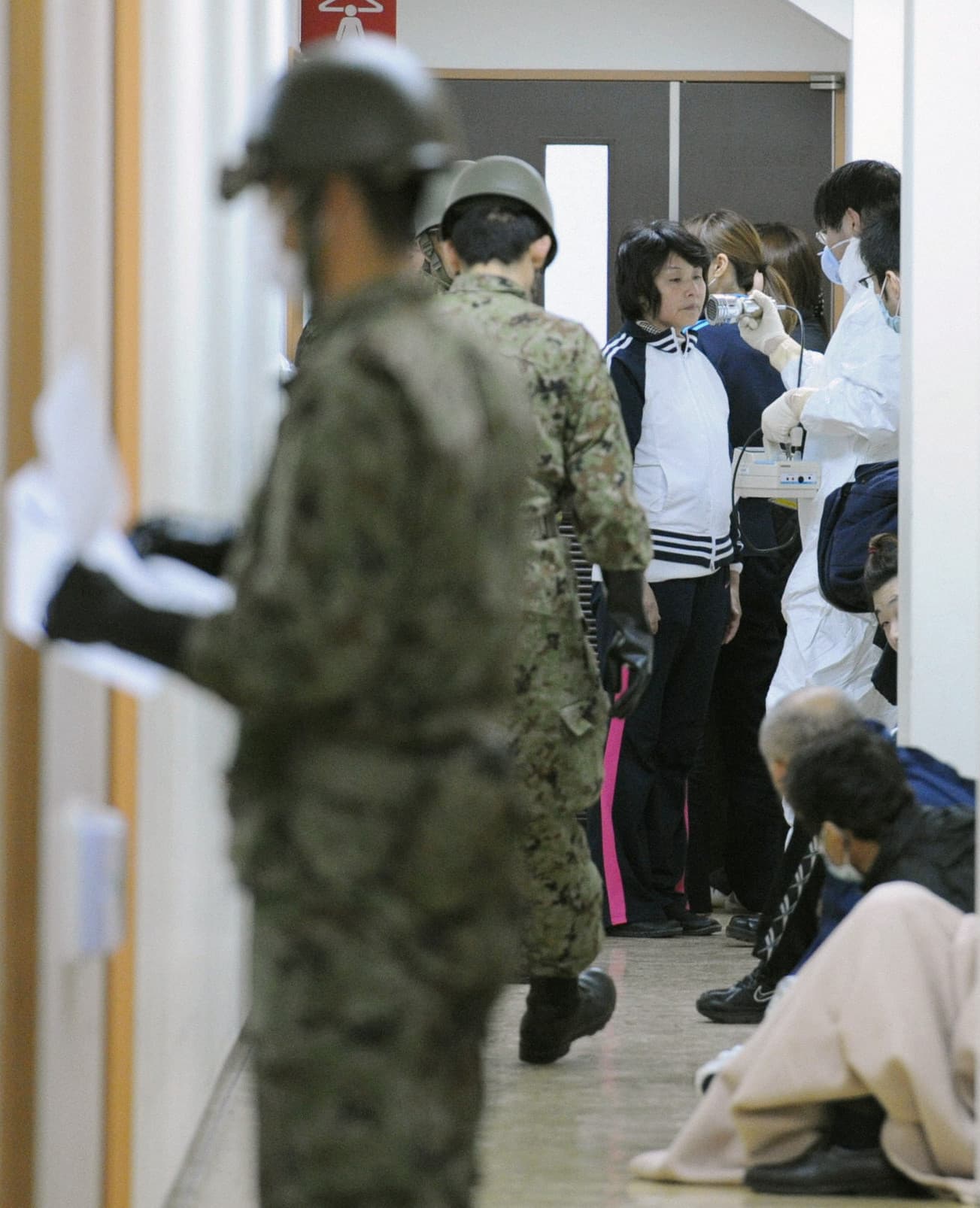 2011年3月13日，從福島緊急撤離的災民（中）在庇護所接受輻射檢查。（東方IC）