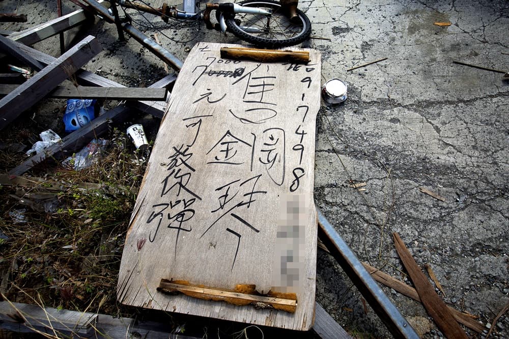 周進田在木板上潦草寫著招生廣告「7000元可教你彈」，可惜至今未有人報名。