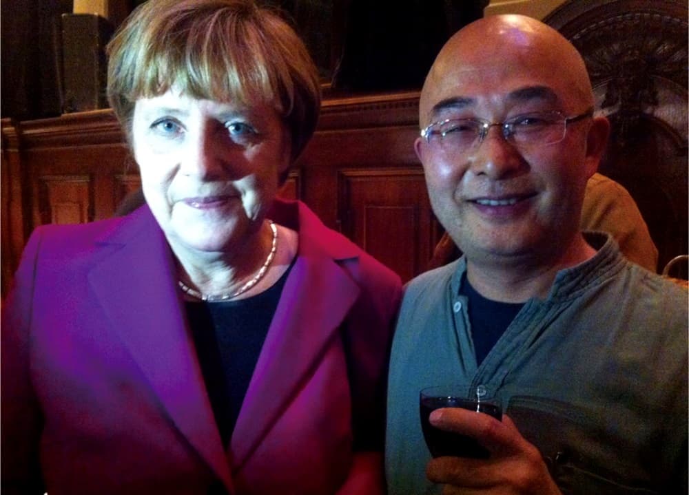 2014年，廖亦武（右）在柏林圍牆倒塌25週年音樂會和德國總理梅克爾（左）聊天，他滿臉通紅，已有醉意。（廖亦武提供）