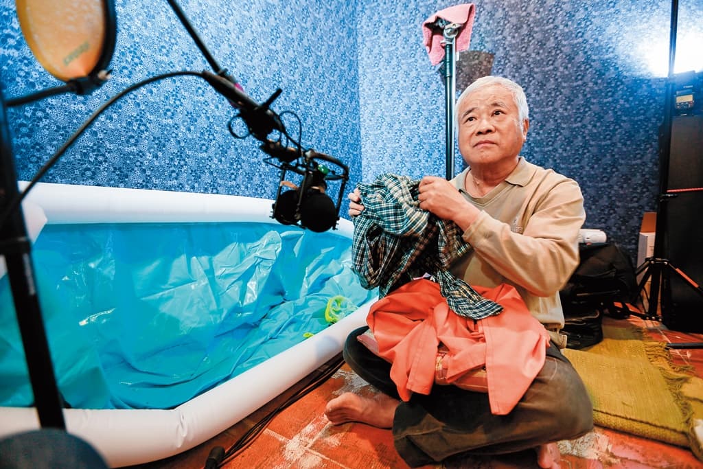 胡定一在錄音室內緊盯螢幕，配合畫面做出各種聲音，如圖中他錄下衣服抖動的音效。