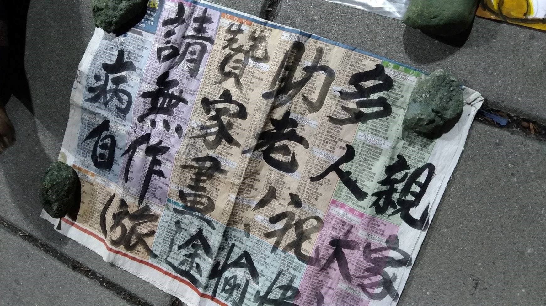 街友阿伯用報紙寫的賣藝看板。（時代力量三民區議員參選人林于凱提供）