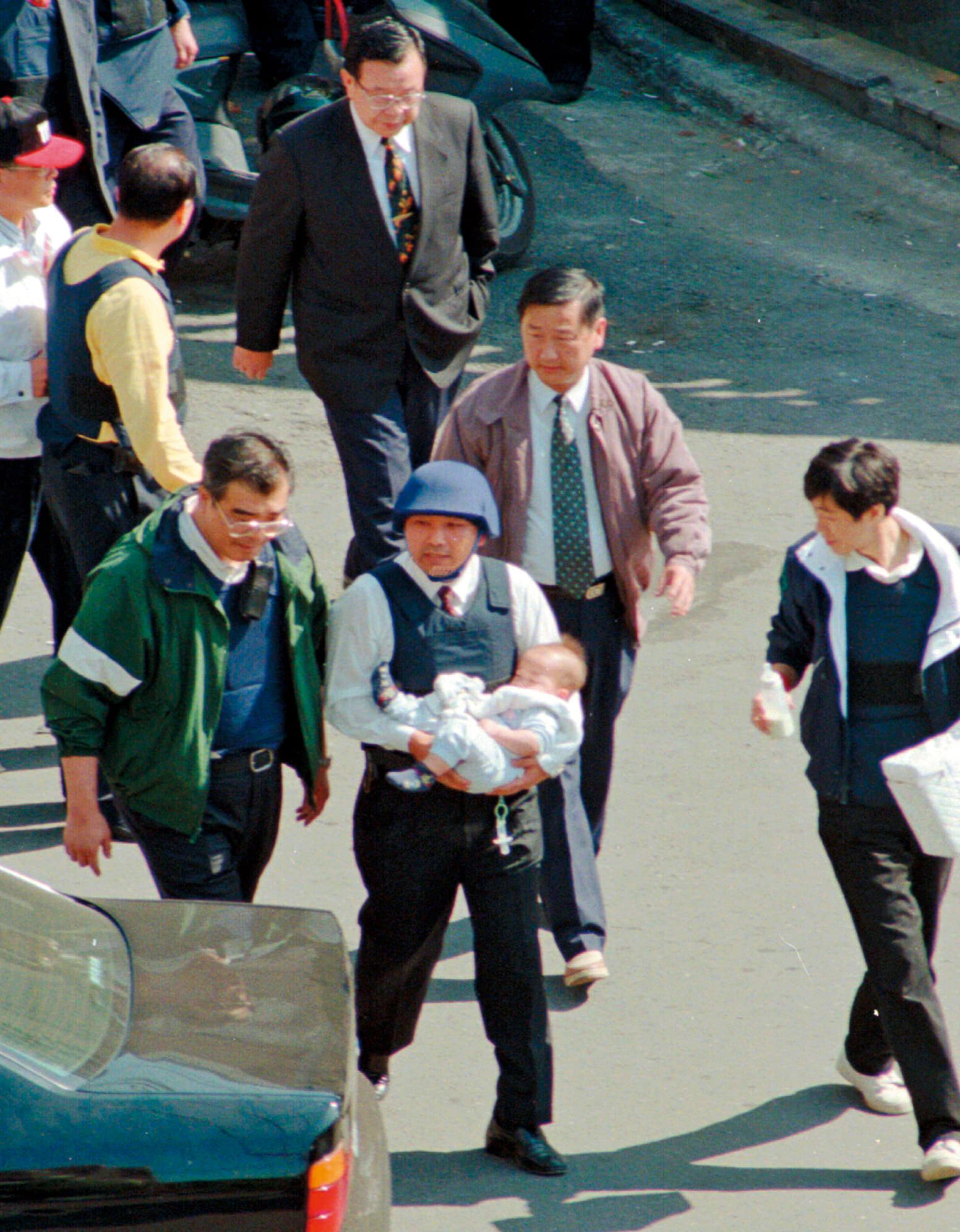 侯友宜（戴帽者）抱著南非武官的女兒。1997年，他進入南非武官官邸營救遭陳進興挾持的人質，因而聲名大噪。