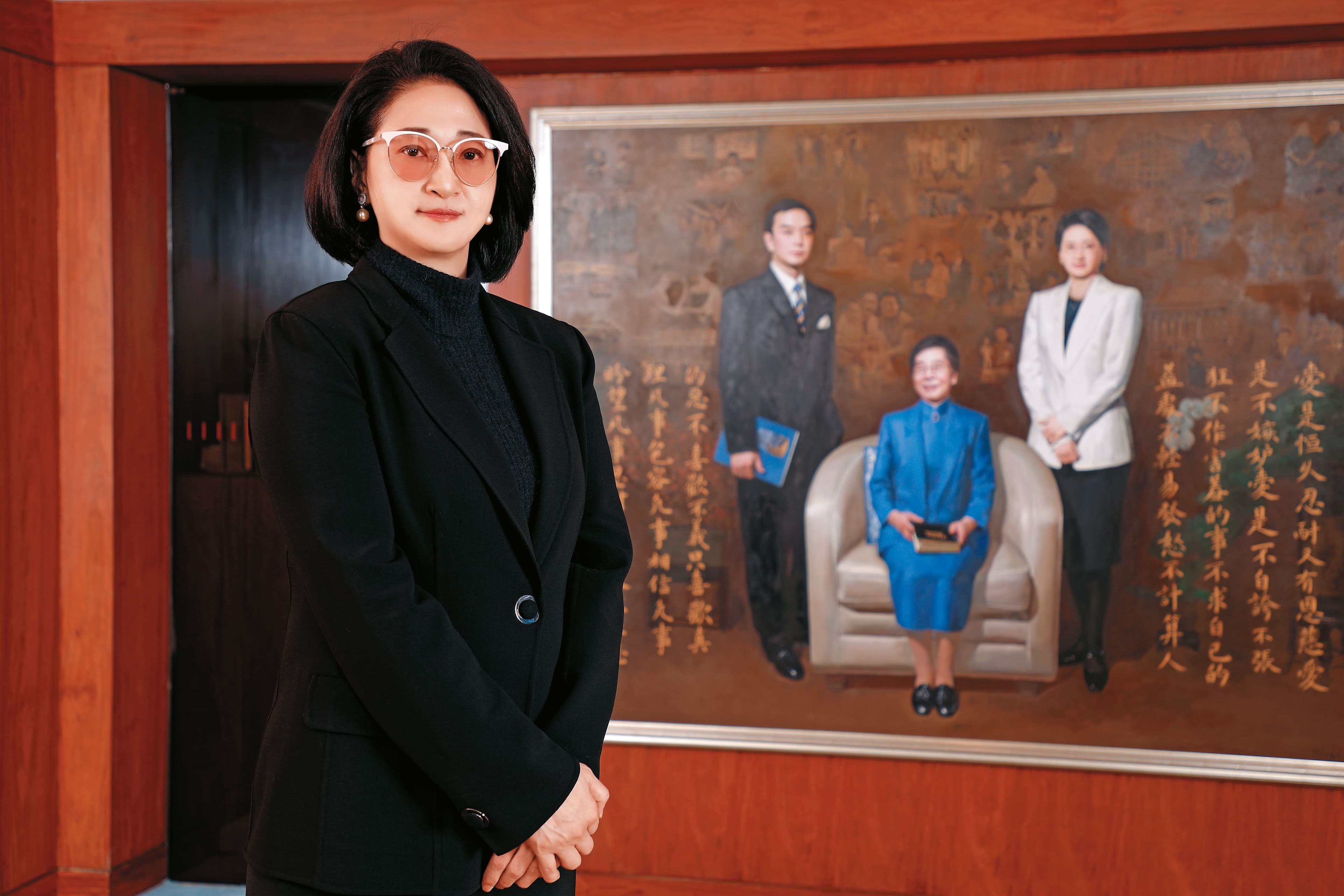 站在與婆婆吳舜文、夫婿嚴凱泰畫像前，嚴陳莉蓮要繼續圓「國車國造」夢想。（裕隆提供）