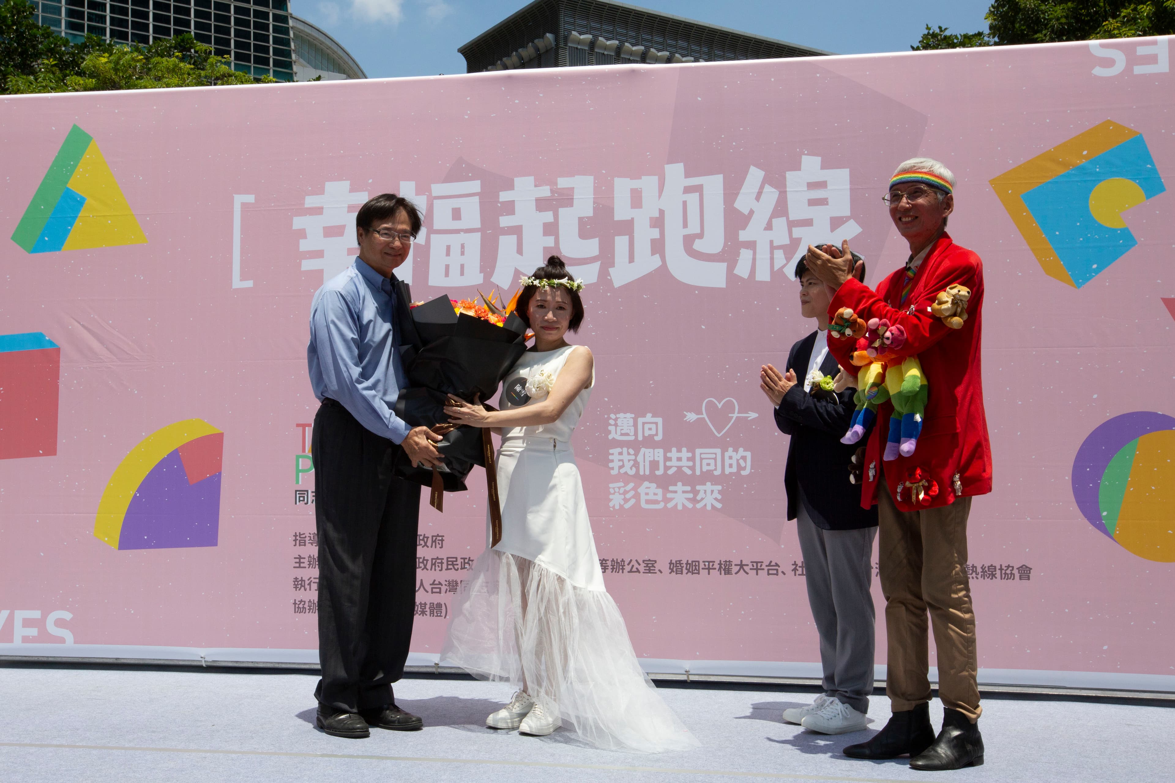 作家陳雪（左二）與伴侶早餐人（右二）辦理結婚登記，北市由民政局長藍世聰（左一）送花祝賀