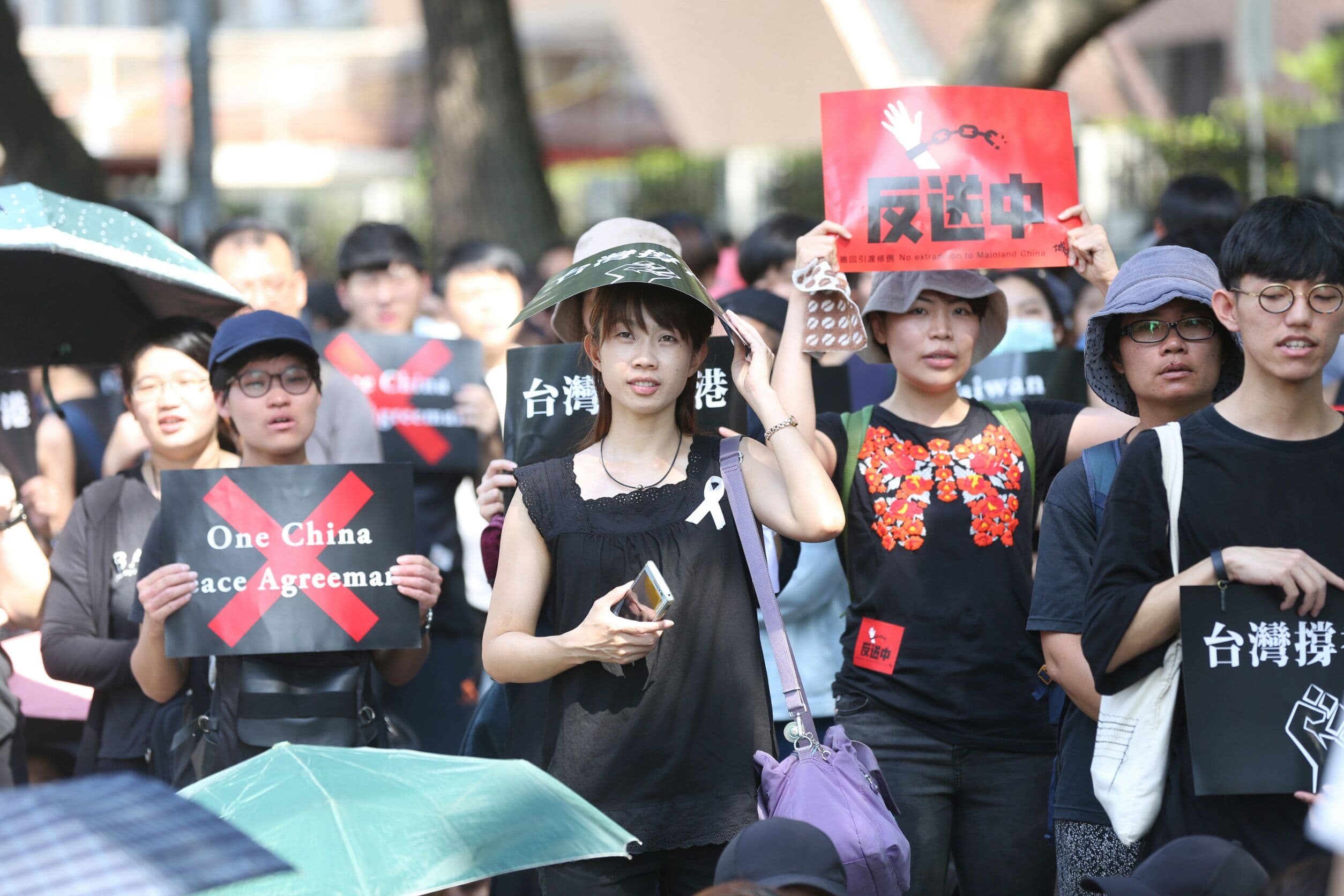 現場民眾除了身穿黑衣綁上白絲帶，紛紛舉起「台灣撐香港」「反送中」等標語。