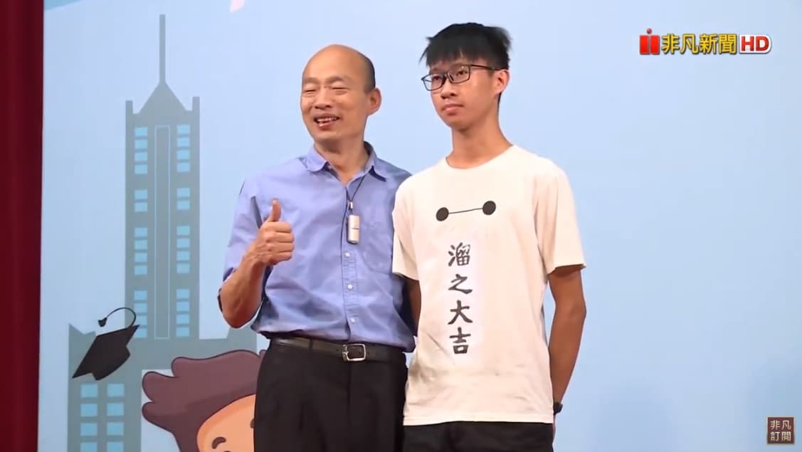 黃同學穿著「溜之大吉」T恤上台與韓國瑜合照，希望市長不要去選總統。（翻攝自USTV 非凡電視YouTube頻道）