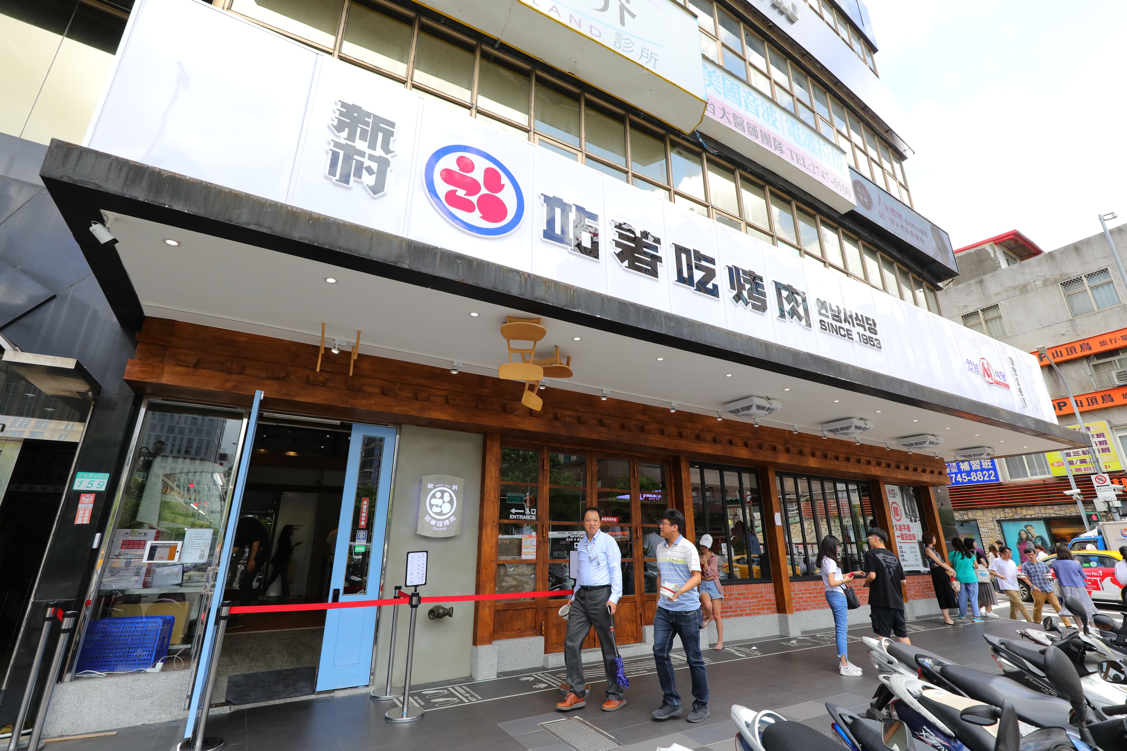 「新村站著吃烤肉」的白底、黑字招牌，在人來人往的忠孝東路上格外醒目。