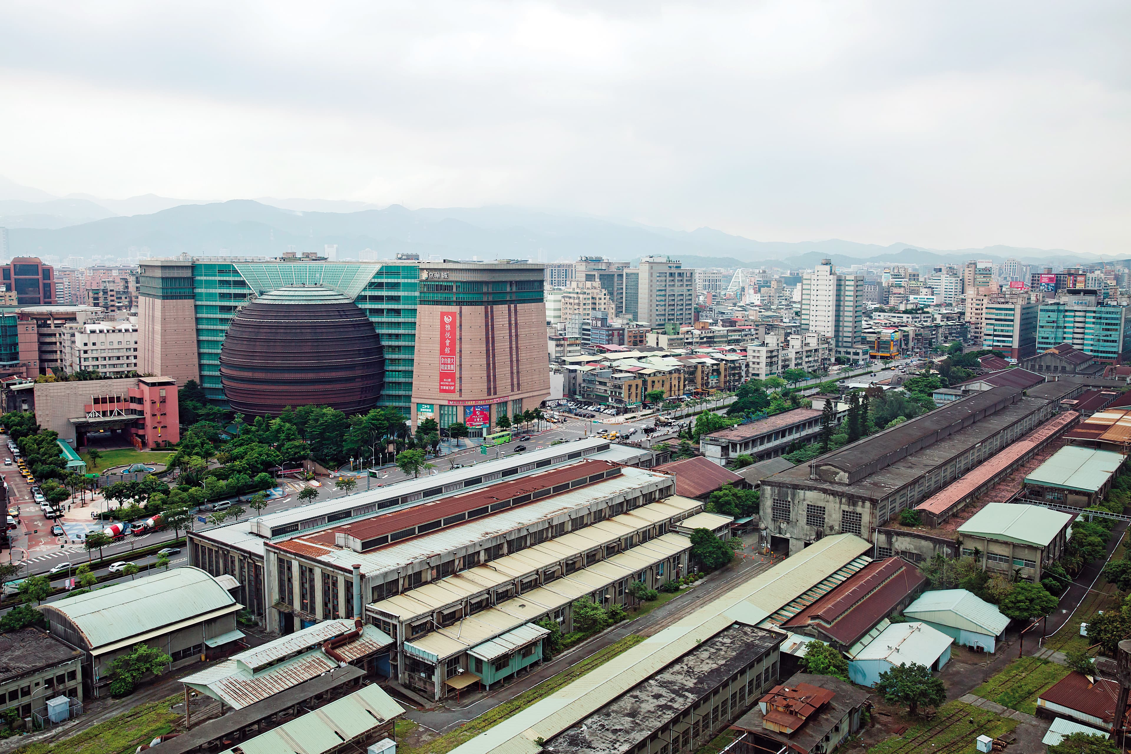 京華城開幕18年卻慘淡經營，市場盛傳原因之一是緊鄰的台北機廠長年閒置未活化，阻斷商場與信義區人潮的連結。