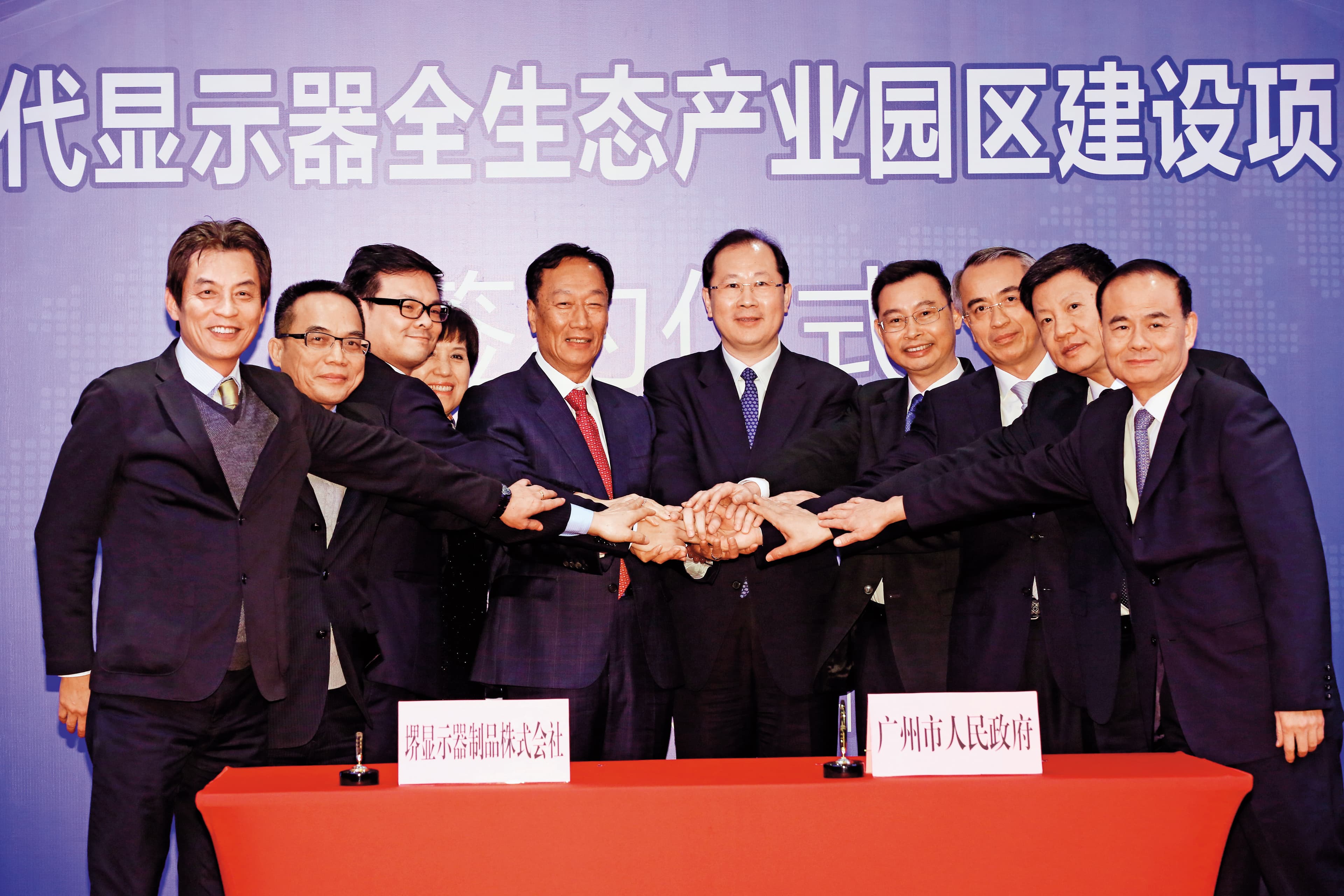 2016年底，郭台銘（中）親自飛往廣州，與廣州市政府簽訂10.5代線顯示器合作協議，投資金額高達人民幣610億元。