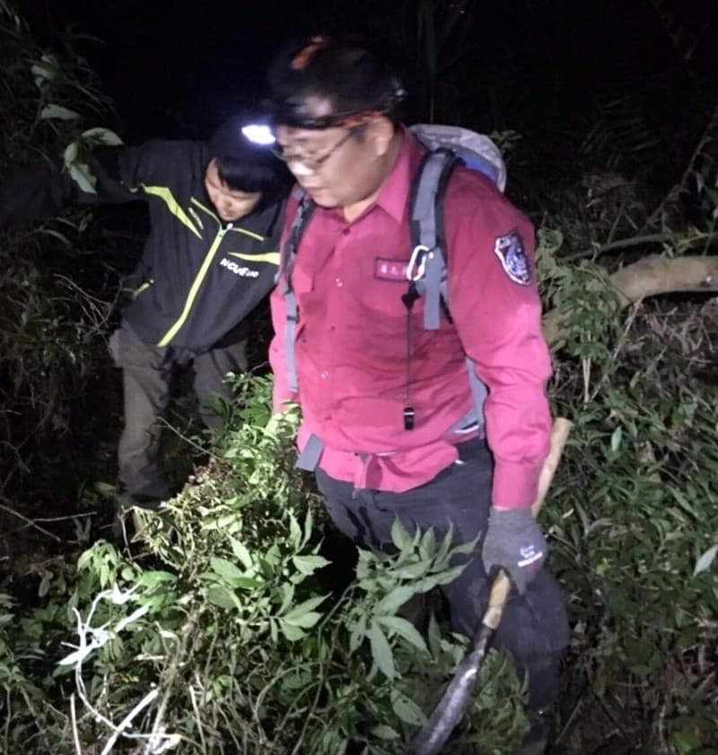 救援人員手持鐮刀闢路上山救人。（消防局提供）