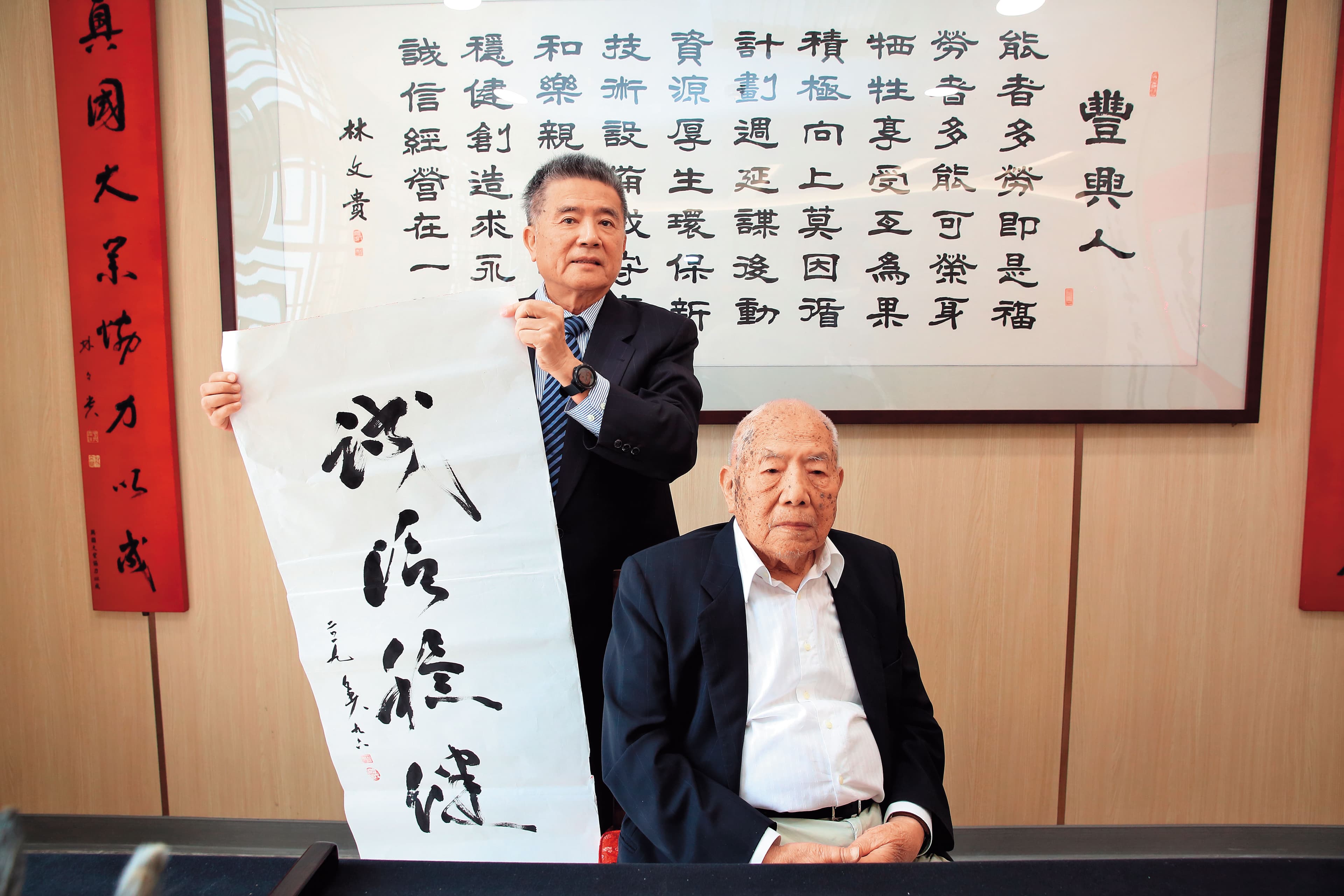 林文貴（右）在紙上寫下「誠信穩健」，提醒下一代經營公司不能投機取巧。