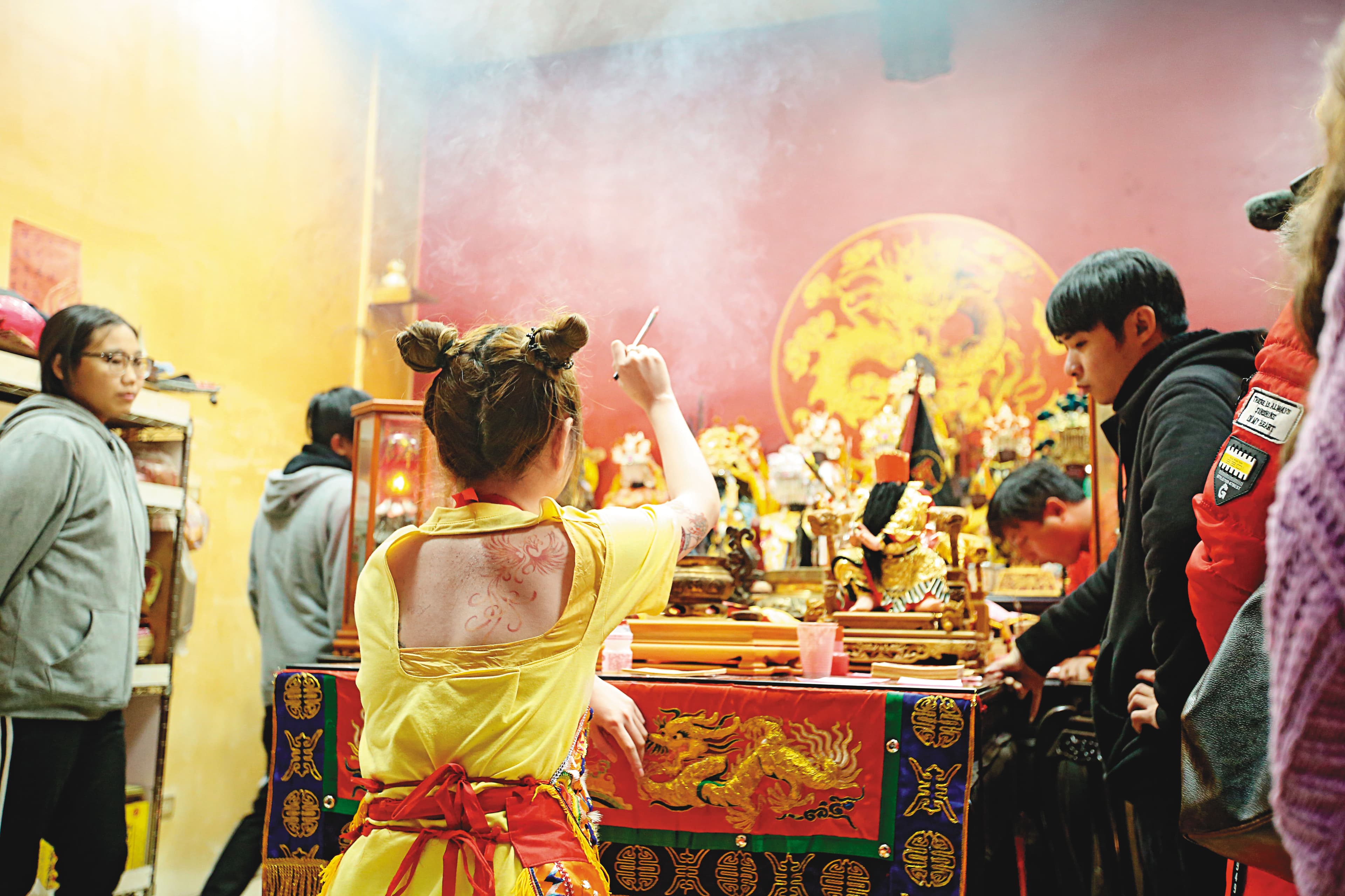 正妹乩童手拿毛筆、蘸上硃砂墨，在空中揮舞，準備替信眾開符令。