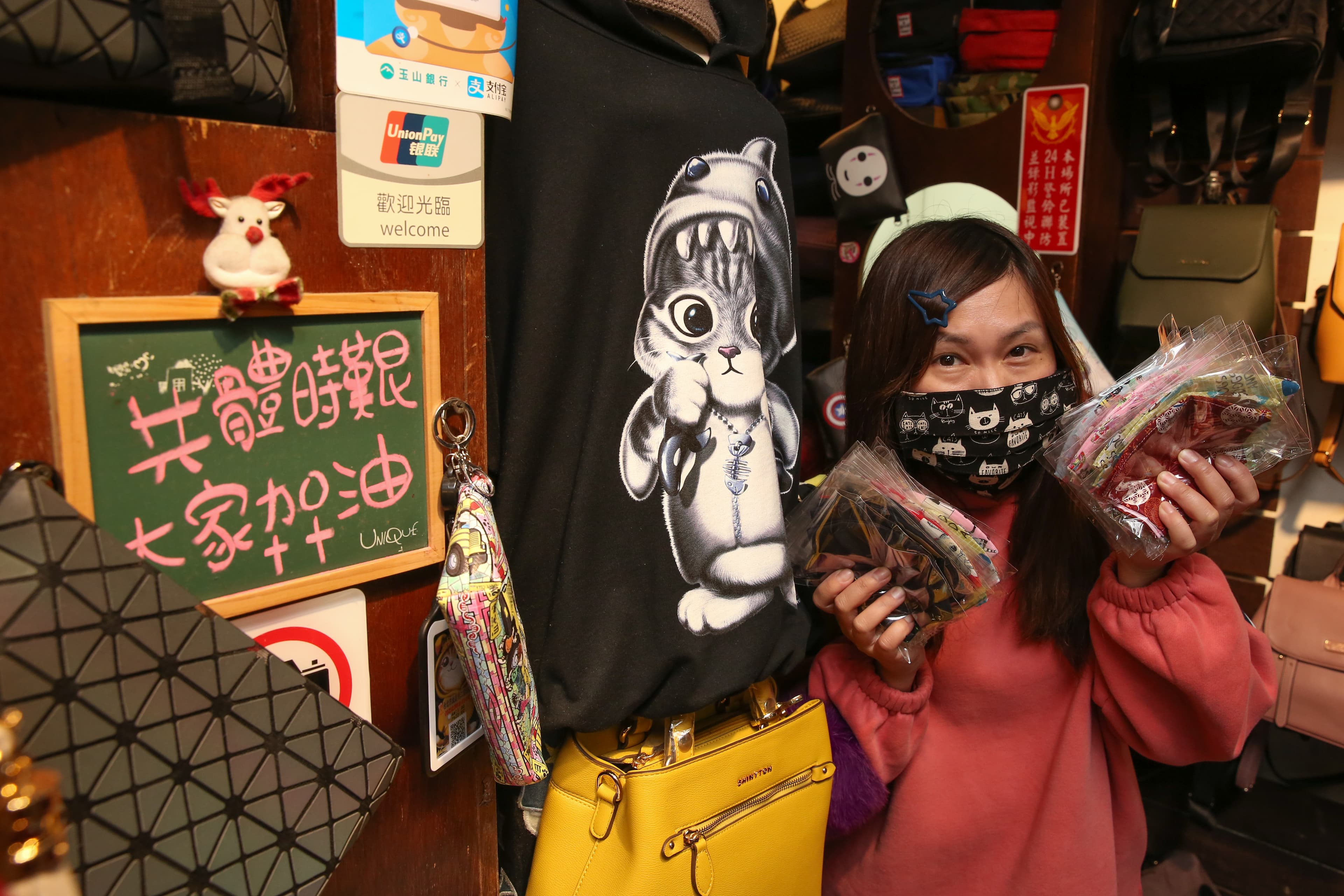 「夜上海」服飾店的老闆娘張玲華受訪，身旁放著一塊寫了「共體時艱，大家加油」的小黑板。