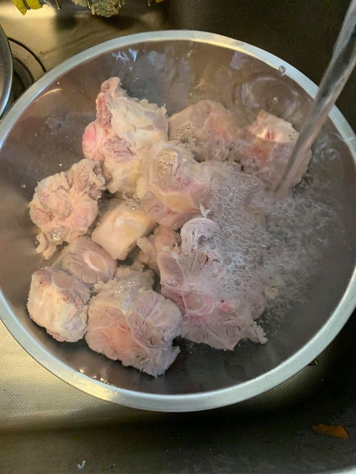 用冷水沖洗汆燙過的牛尾。