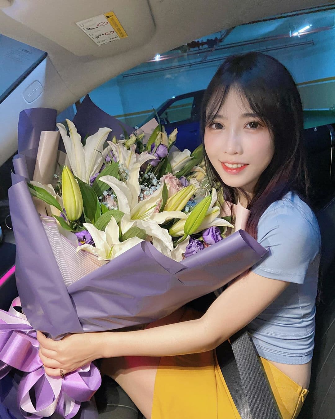 咪妃手拿鮮花在副駕駛座甜笑，背景疑似Joeman的車子。