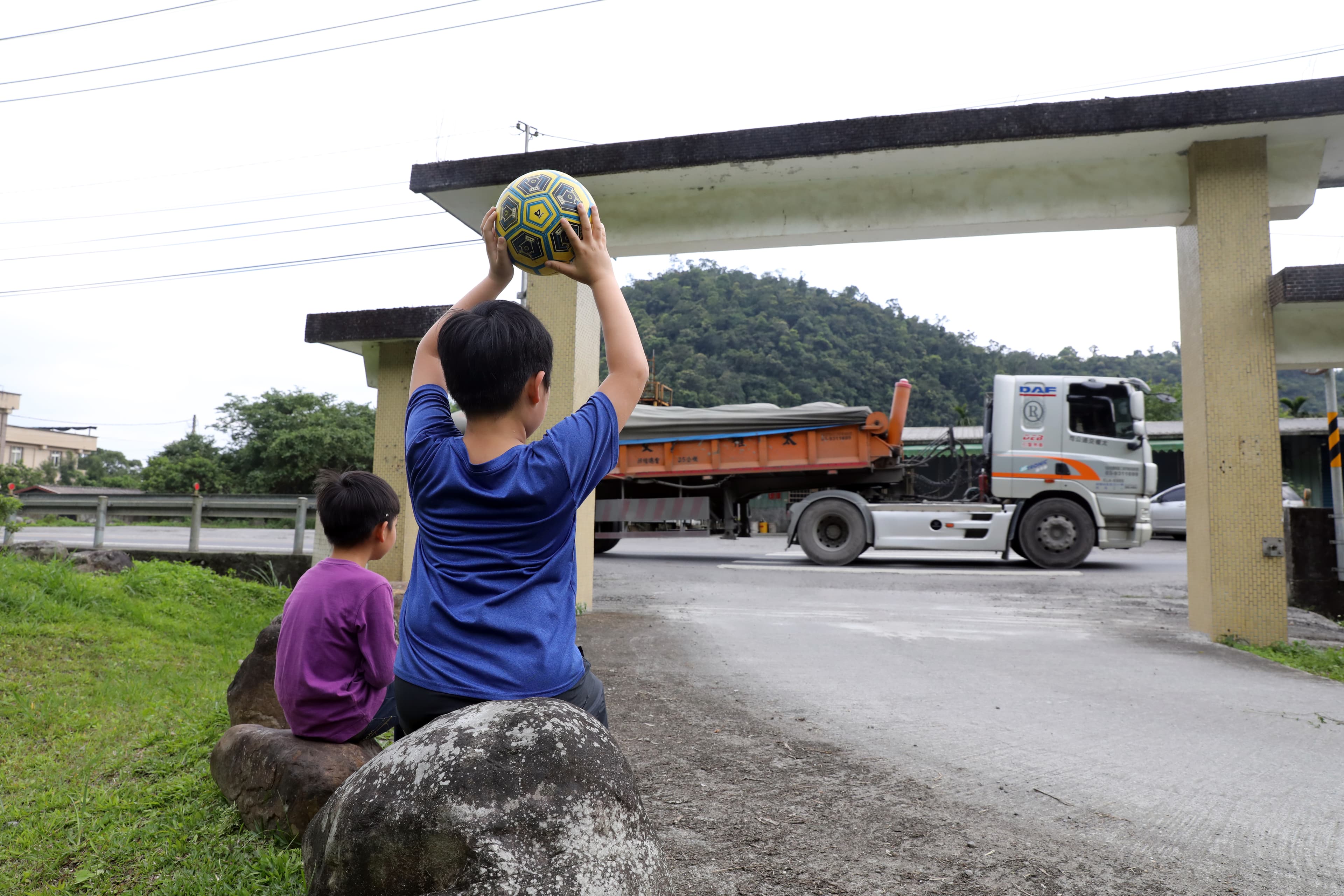村內化育國小校門緊鄰砂石車頻繁穿越的台七線，學生上課、遊戲都擺脫不了砂石車的身影。
