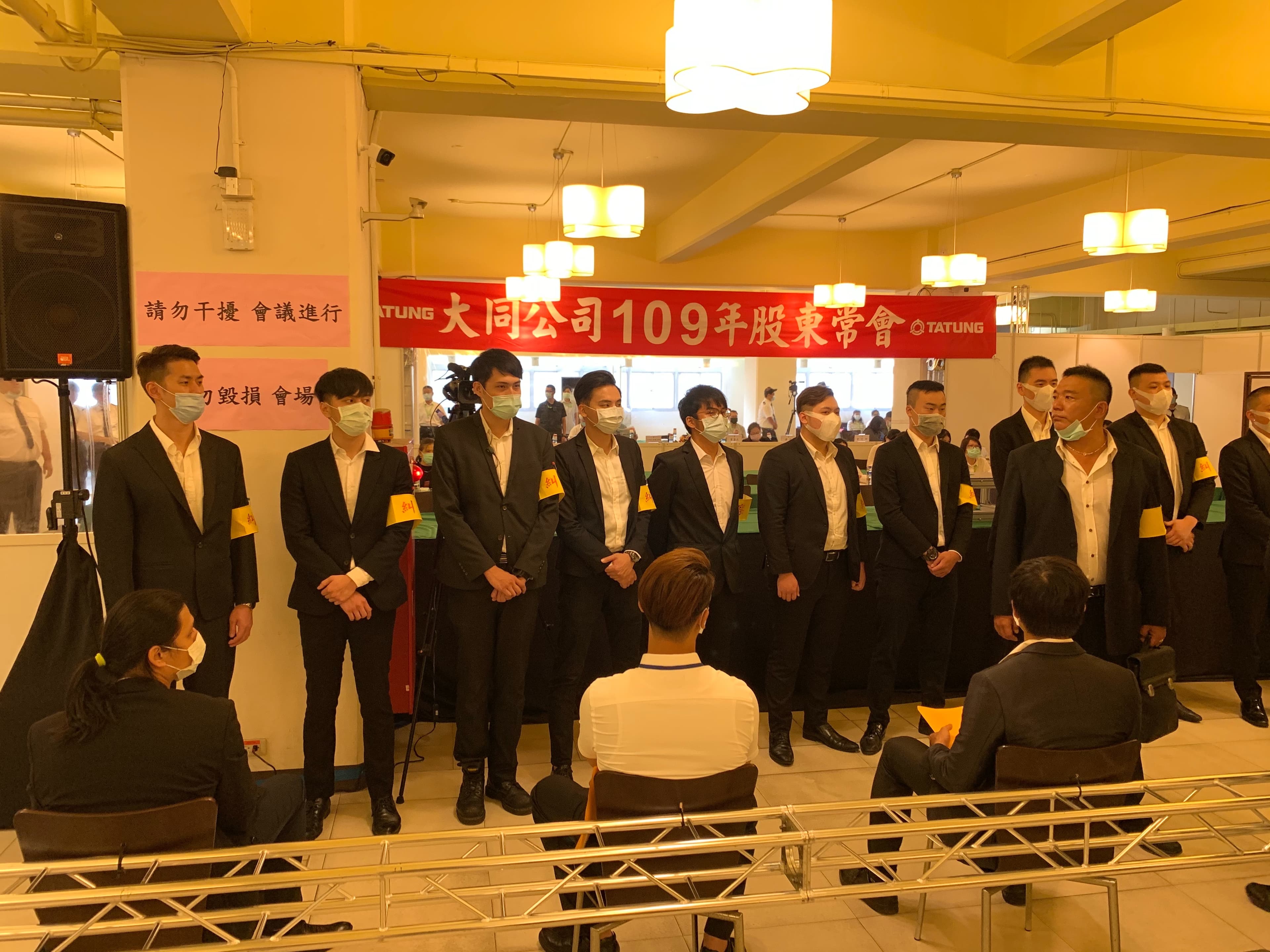 股東會現場站滿一排黑衣人。