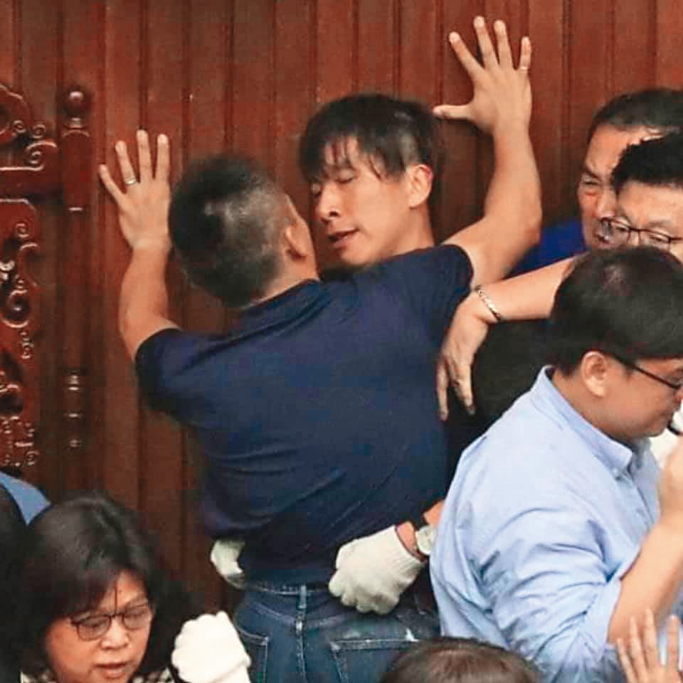 藍綠立委攻防，洪孟楷（前）「壁咚」鍾佳濱（後），   「男」分高下。（翻攝自貓與邪佞的手指臉書）