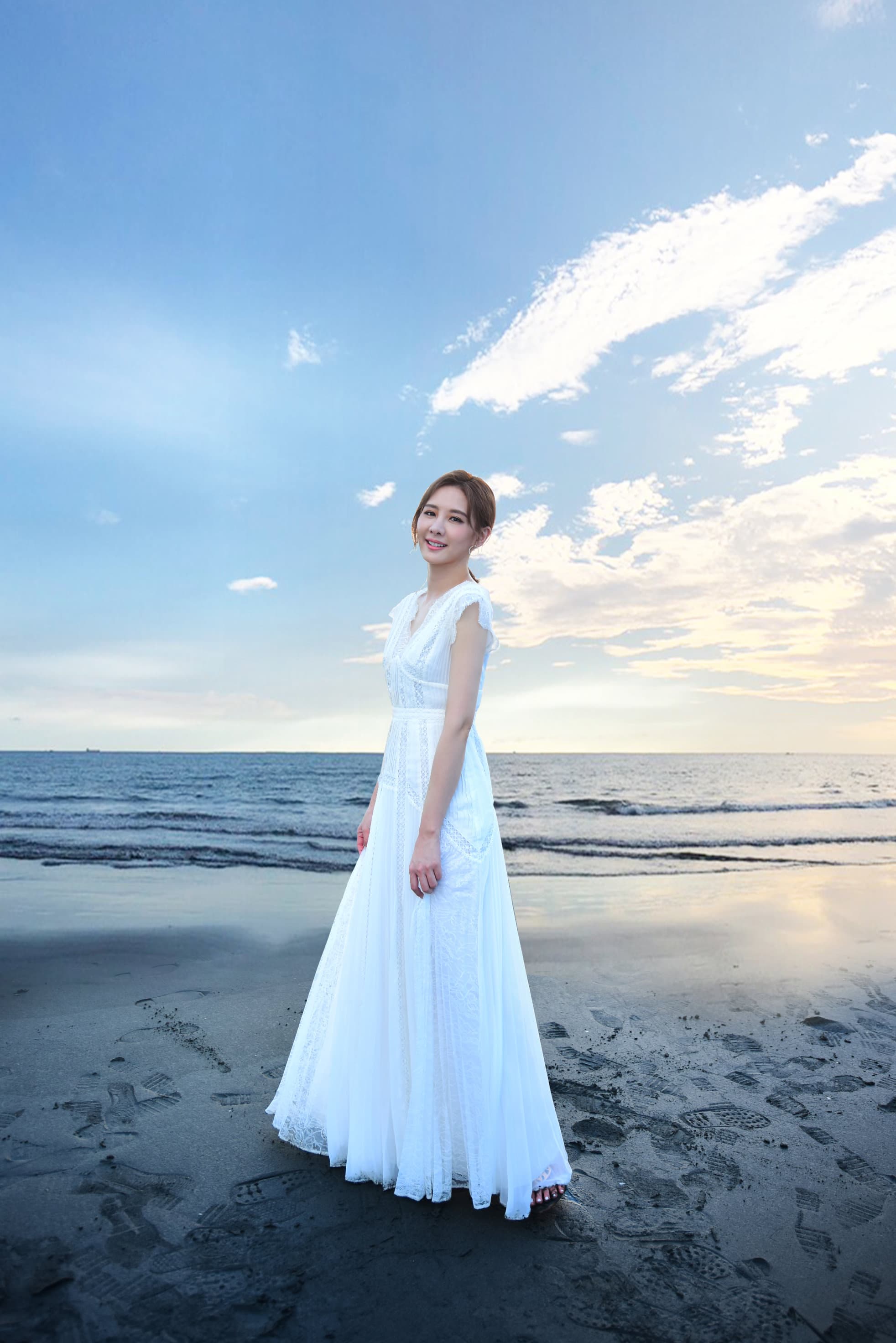 安心亞身著白色洋裝漫步沙灘，直呼想在海邊拍婚紗。（環球唱片提供）