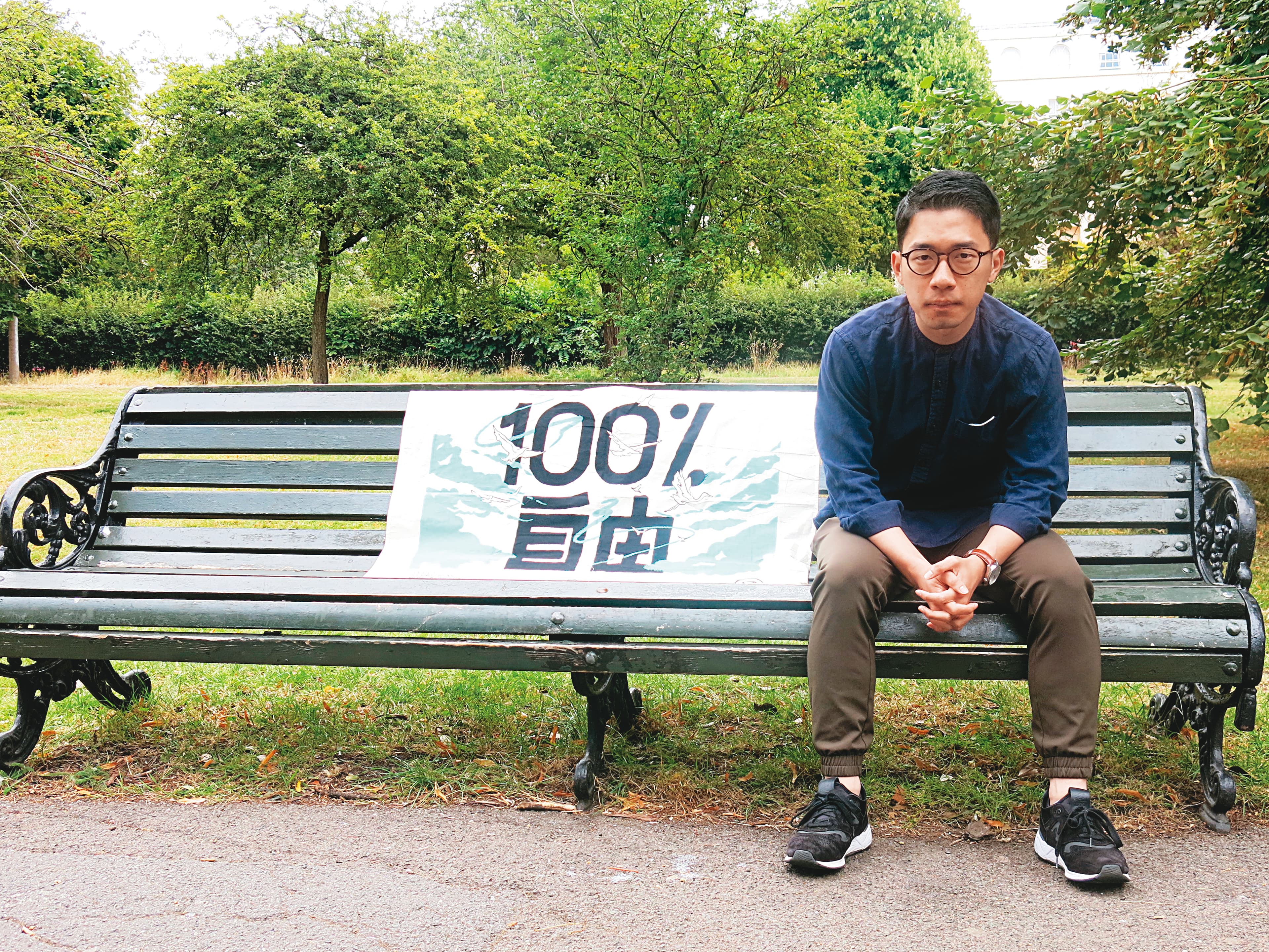 已解散的香港眾志曾引用鄭南榕「爭取100％自由」名言製作旗幟，羅冠聰如今進行國際倡議也帶著這面旗幟，香港的民主自由已是他一生的追求。（陳彥廷攝）