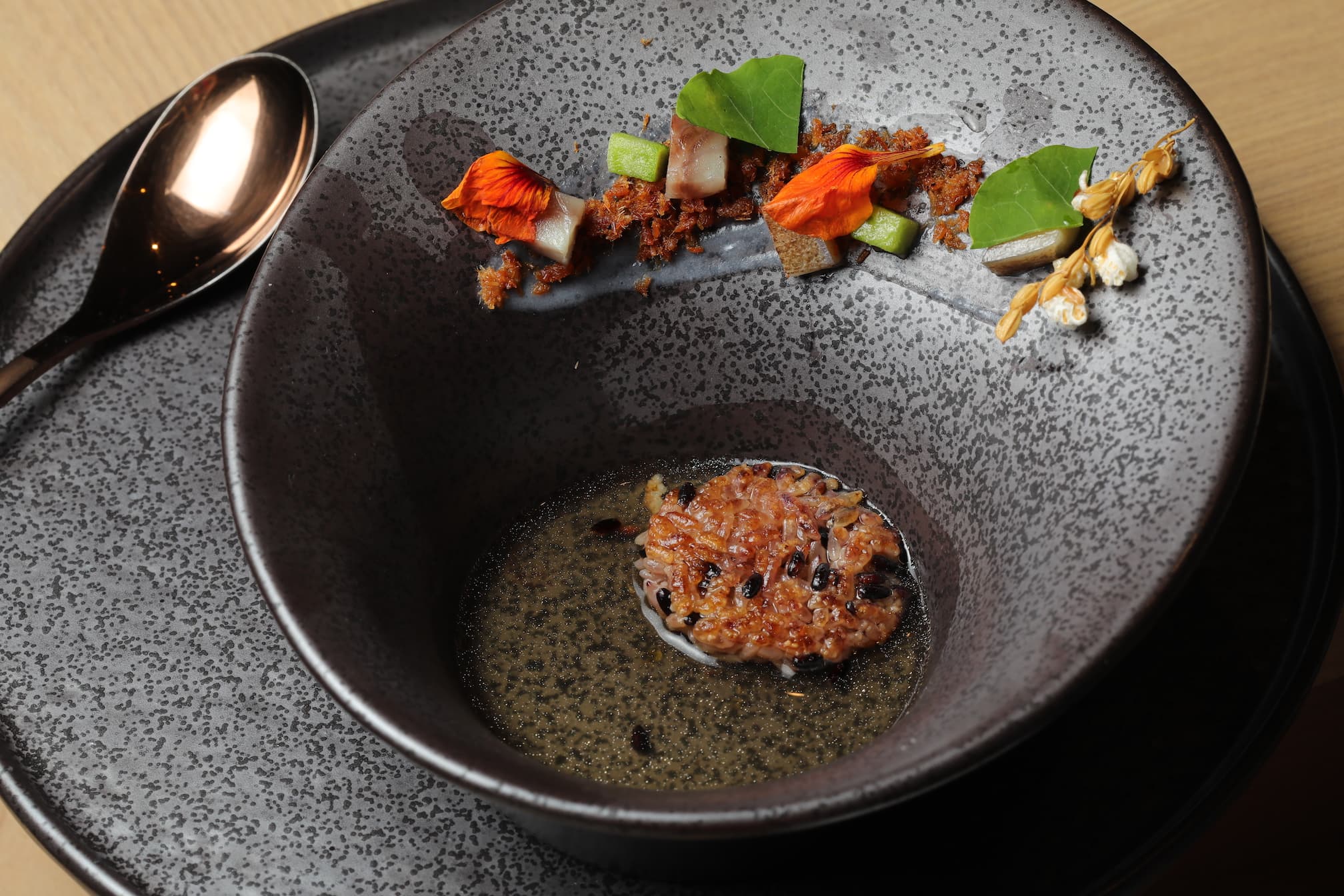 將煙燻普洱茶鰻骨高湯淋入有魚鬆、熟成鯖魚的醋飯鍋粑餅。
