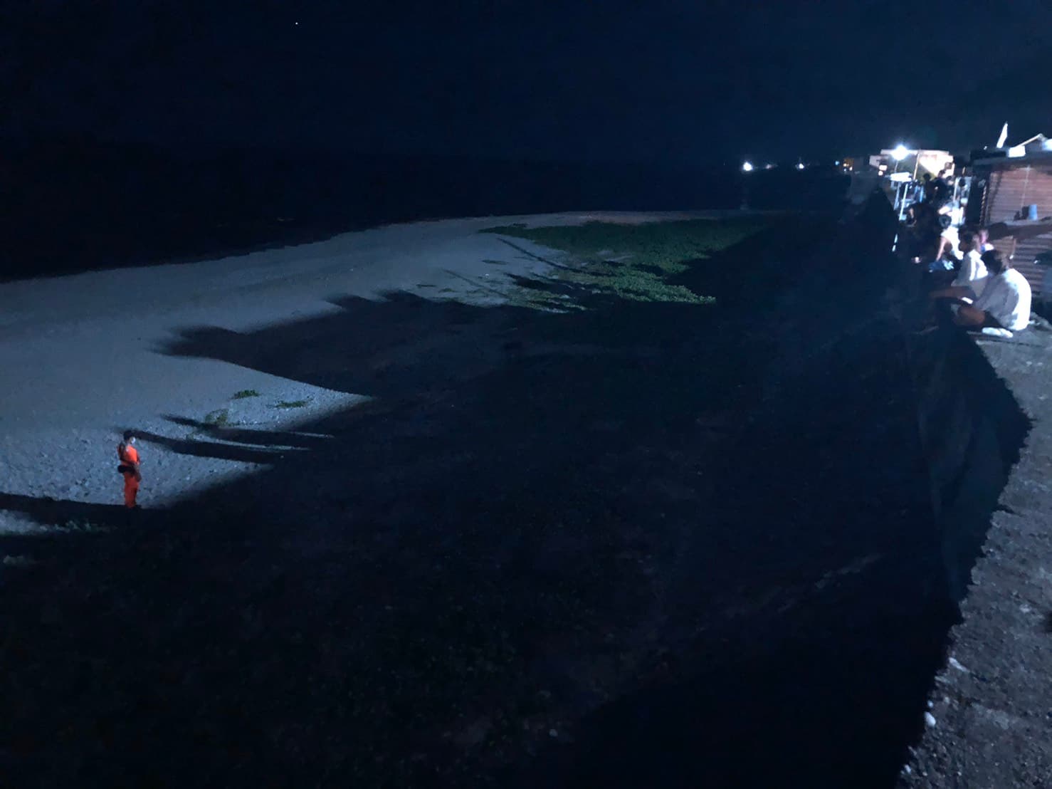 海巡人員在距離綠蠵龜約10公尺處進行戒護，並向周遭遊客柔性勸導切勿大聲喧嘩及開啟任何燈源等事項，以維持現場環境使綠蠵龜能順利產卵。（海巡署提供）