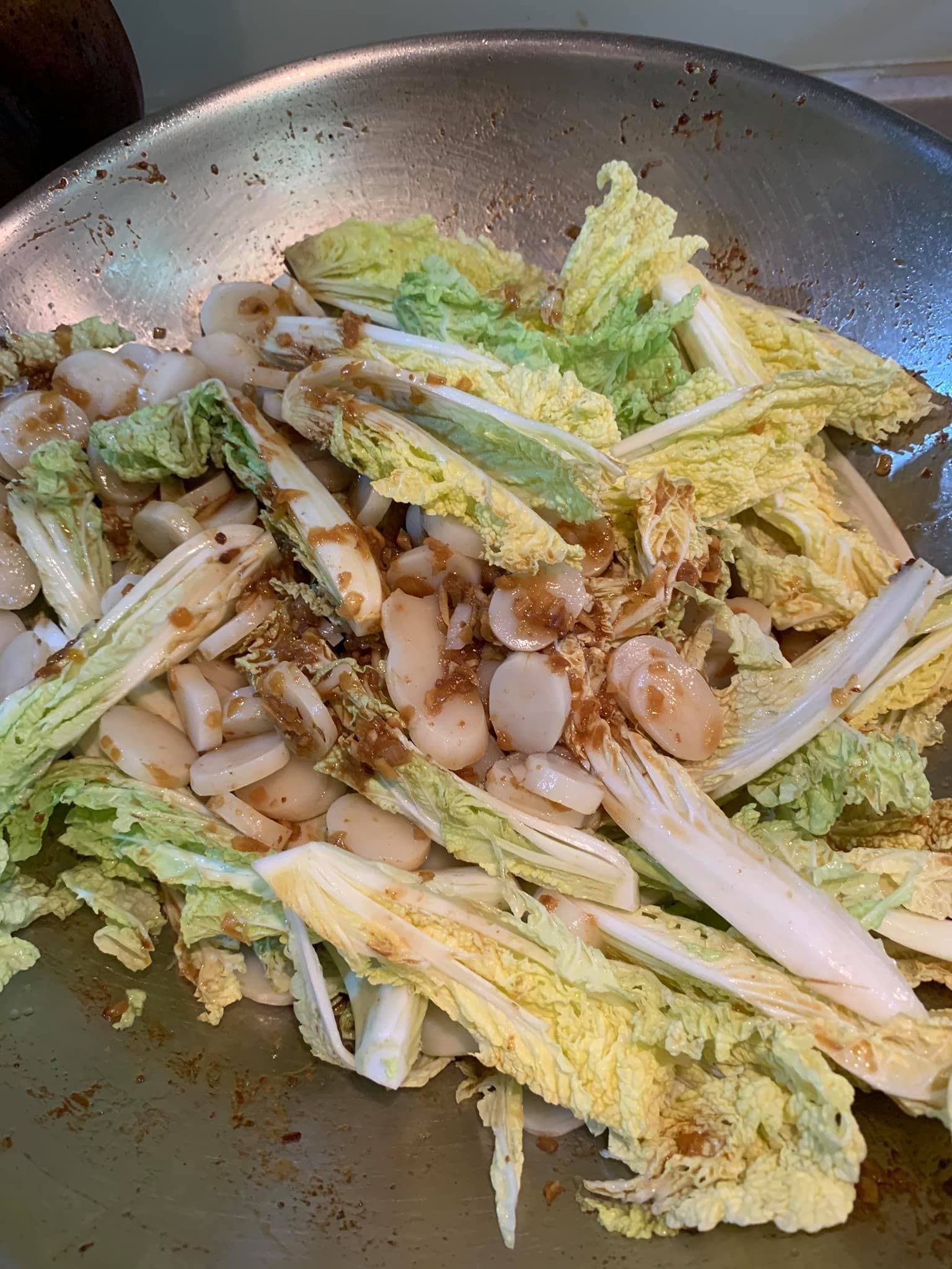 將蟹塊撈出，留下的醬汁炒年糕與蔬菜。
