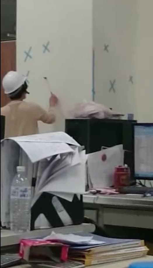 驗收時，主驗官群拿著鎚子四處敲打牆面。（讀者提供）