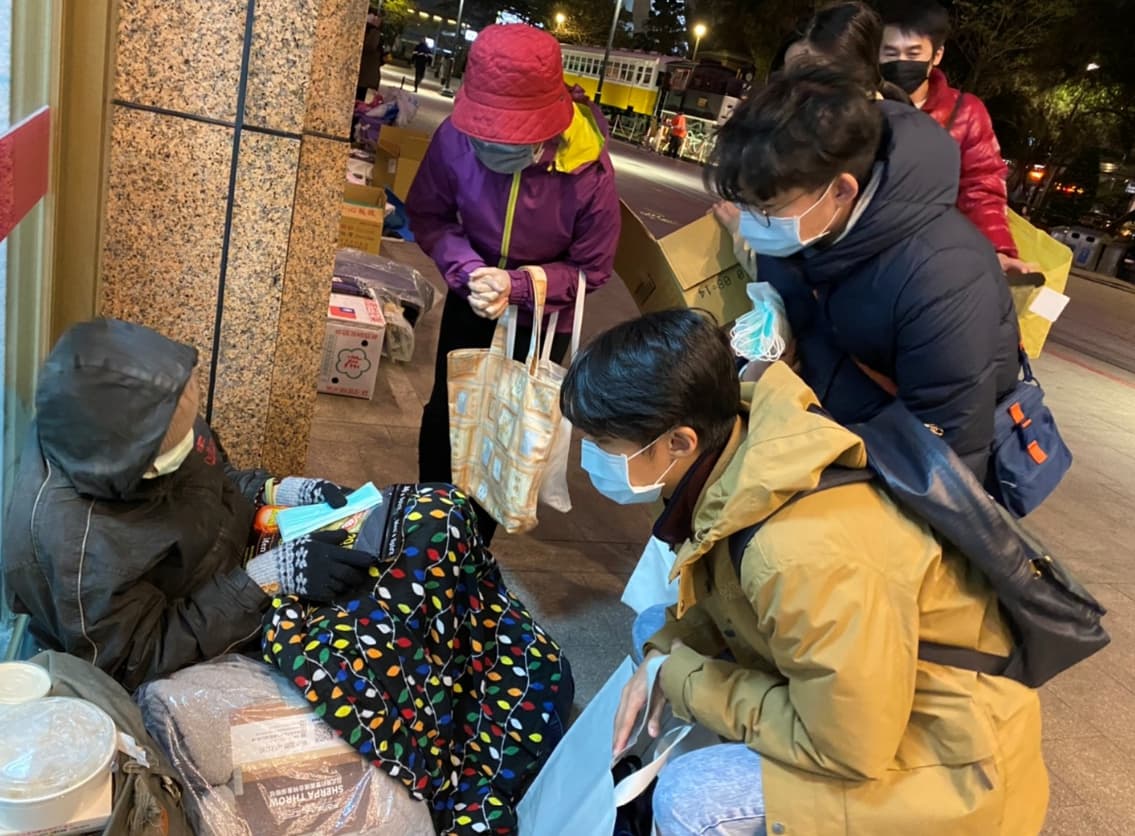 慈濟志工陳雲貞、慈科大校友趙軒、趙悅、張家瑜（左二起）送口罩及暖暖包給街友。（慈濟提供）
