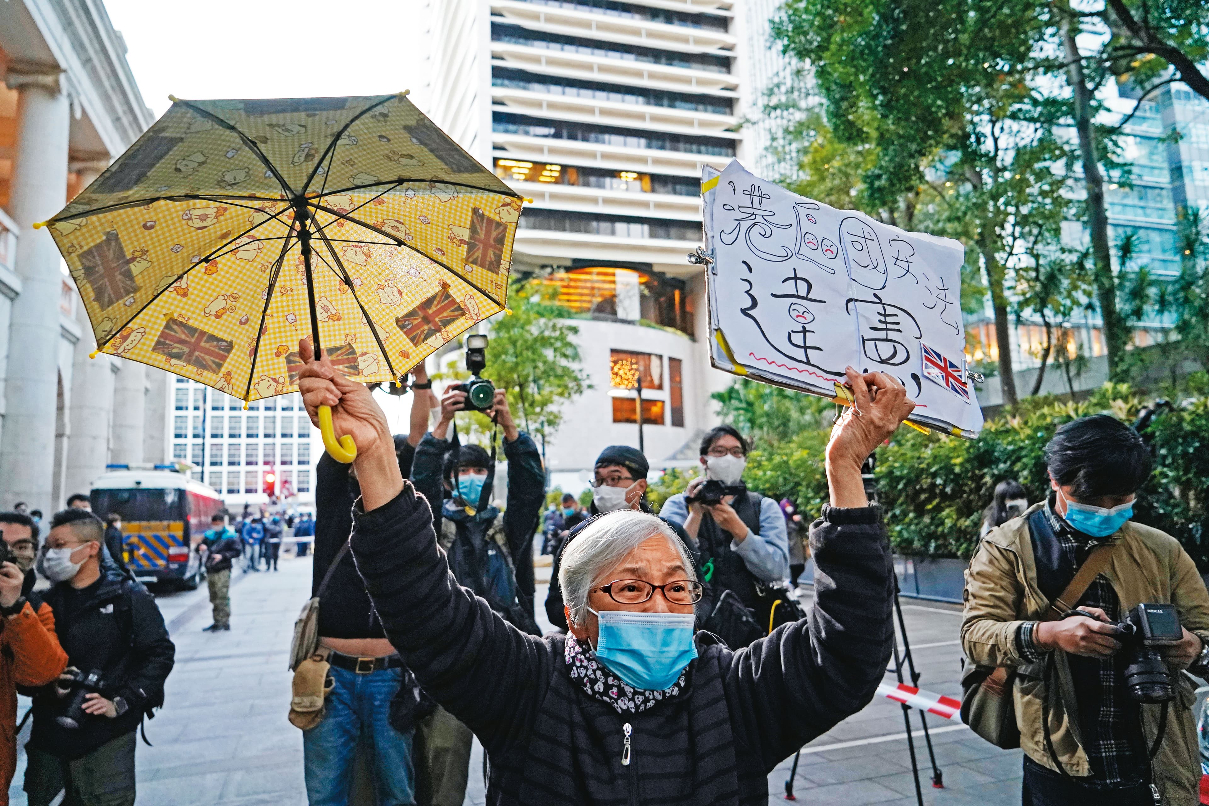 香港知名社運人士「王婆婆」曾聲援黎智英。圖為她高舉黃傘與自製的「港區國安法違憲」標語牌。（達志影像）