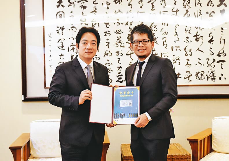 為鼓勵超級菁英回台，國發會2018年核發第一張「就業金卡」給陳士駿（右）。左為時任行政院長的賴清德。（國發會提供）