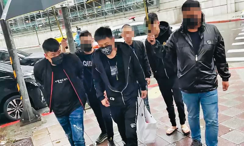 北投媽祖文化協會上月遭人開槍，楊姓（左3）及郭姓（左1）嫌犯搭乘小弟駕駛的名車赴警局投案，並由小弟撐傘護送，高調舉止引發議論。（翻攝畫面）