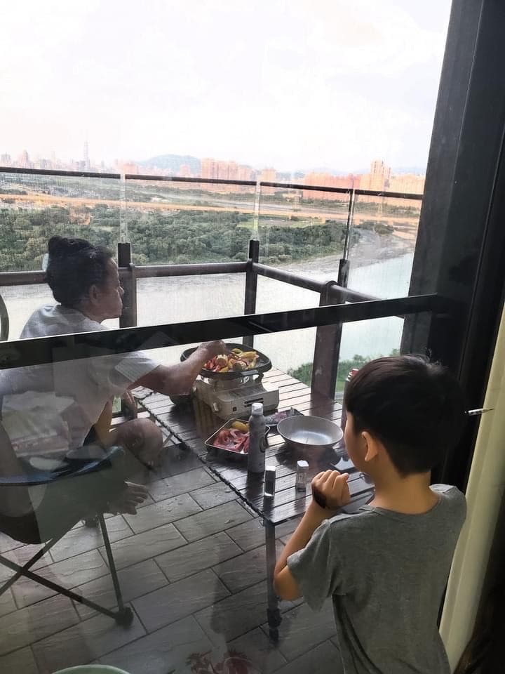 陳仙梅側拍攝影師老公躲在陽台燒烤模樣。（翻攝自陳仙梅臉書）