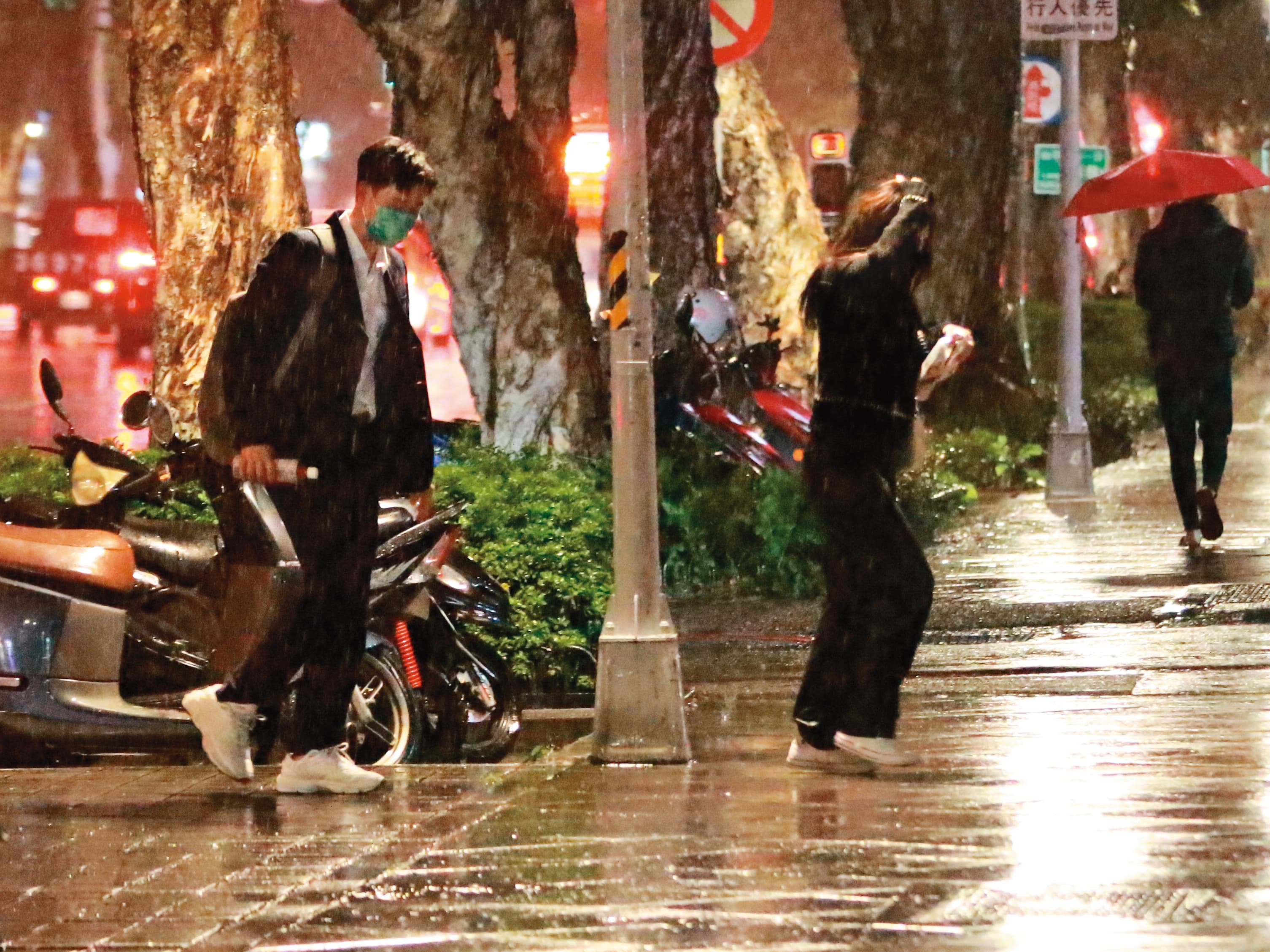 當天飄著細雨，周興哲（左）沒脫下外套為女友遮雨，趙岱新（右）以手護頭疾步走往騎樓。