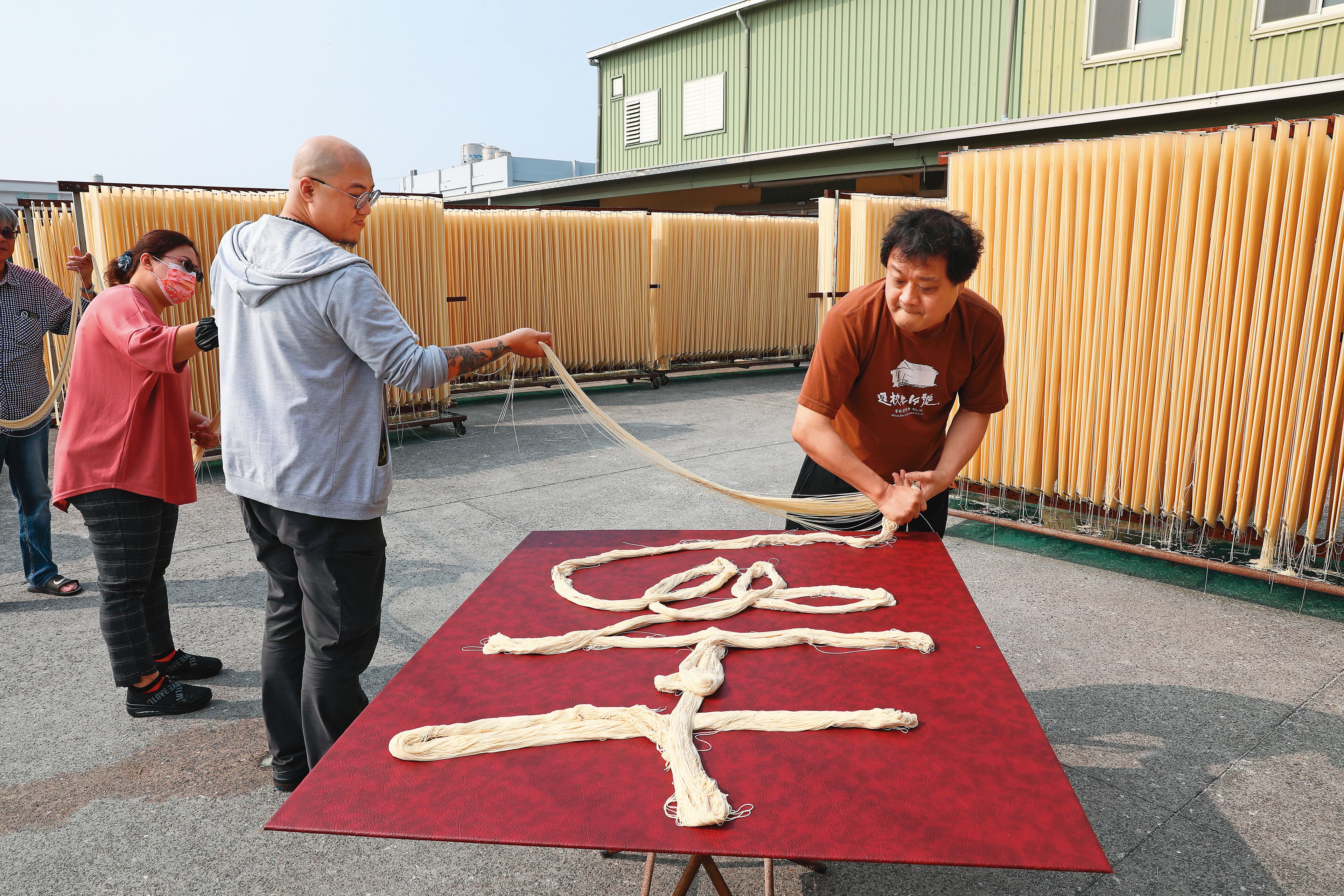 鄉親父老喜愛陳世憲（右）的作品。圖為陳世憲受邀至彰化麵線工廠，以麵線做複合媒材書法創作。