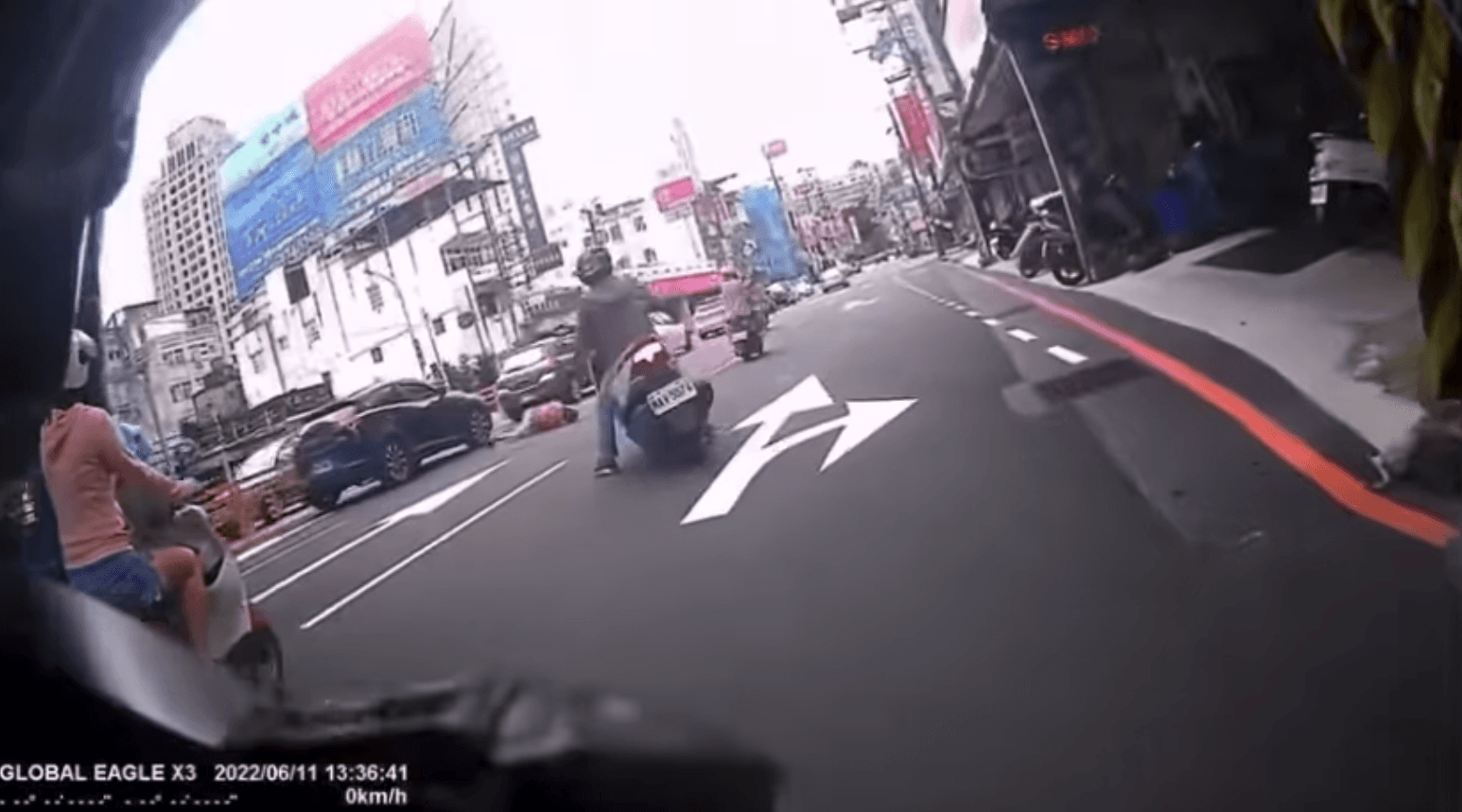 後座婦人跌落路中，後方白色機車騎士上前擋在婦人後方，以防二次車禍。（翻攝爆料公社二社）