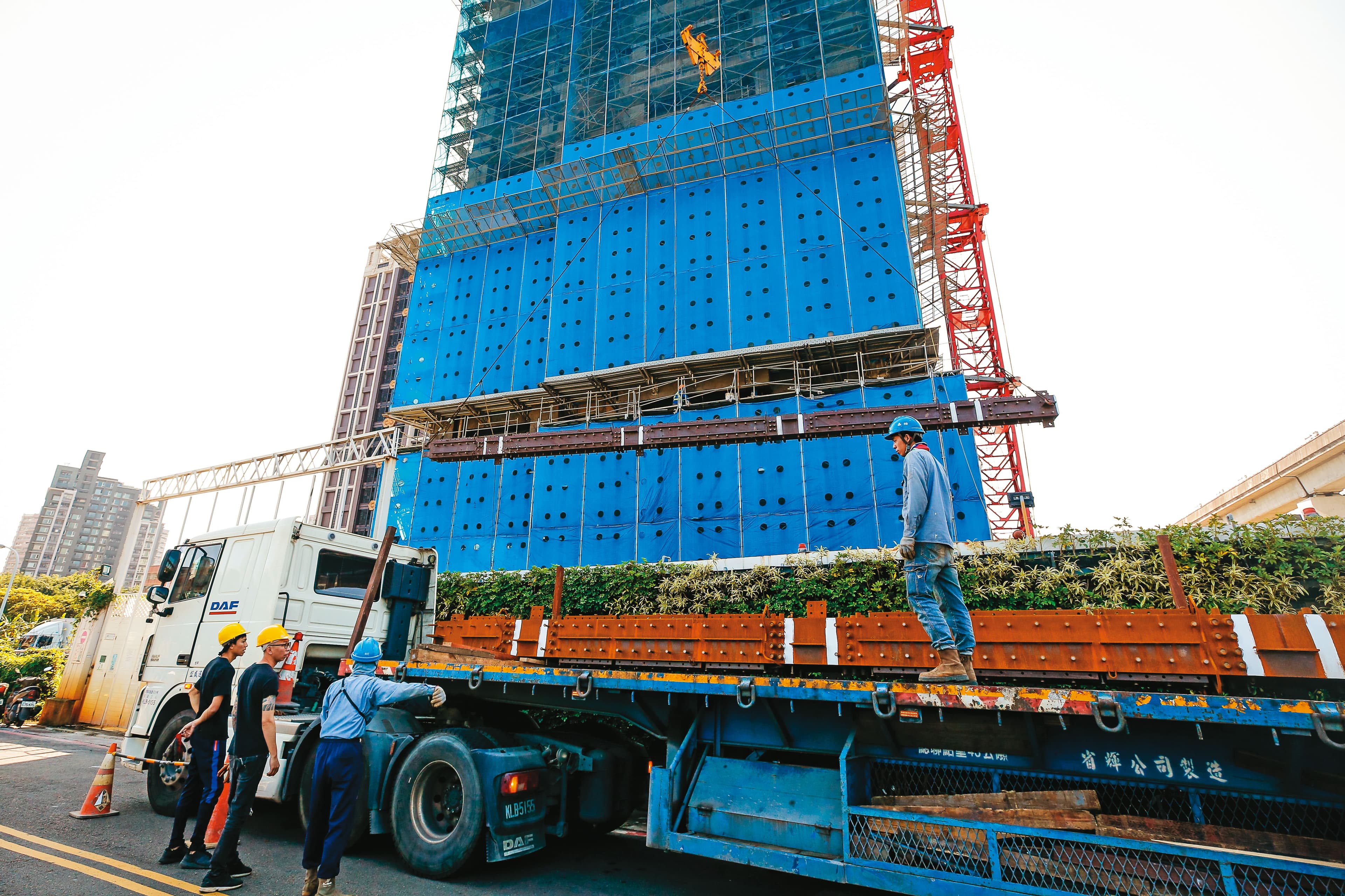 興建台北雙子星相當於蓋1.5座台北101，屆時鋼骨需求可想而知。圖為大型貨車載運鋼骨至某大樓工地。（資料照片）