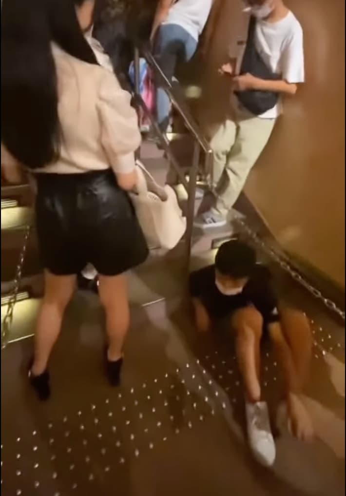 女遊客疑似察覺到少年的異樣，立刻閃向一邊，不過少年卻裝作若無其事趕緊把頭轉向別處！ （翻攝自youtube）