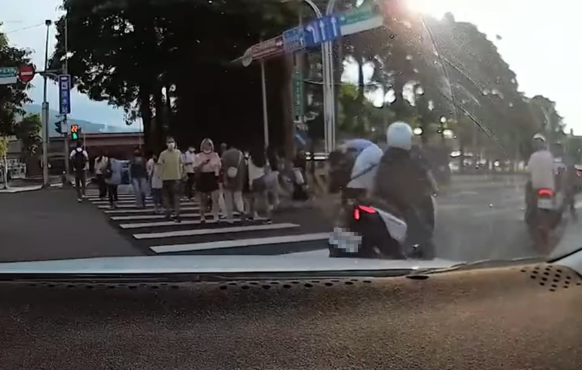 一名機車騎士絲毫沒有減速想直闖通過，眼看就要撞上一名穿襯衫的男子。（翻攝自爆廢公社）