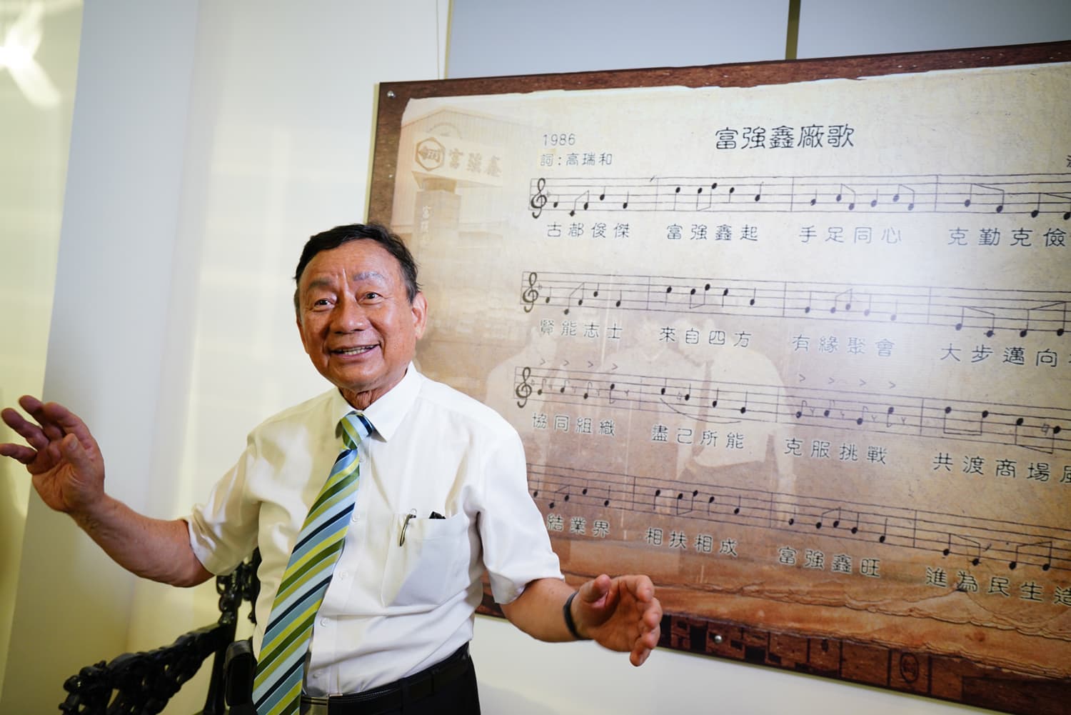 富強鑫大廳的牆面貼著廠歌歌譜，歌詞道盡富強鑫創業史，也藏著王伯壎二個兒子的名字「傑」、「賢」二字。