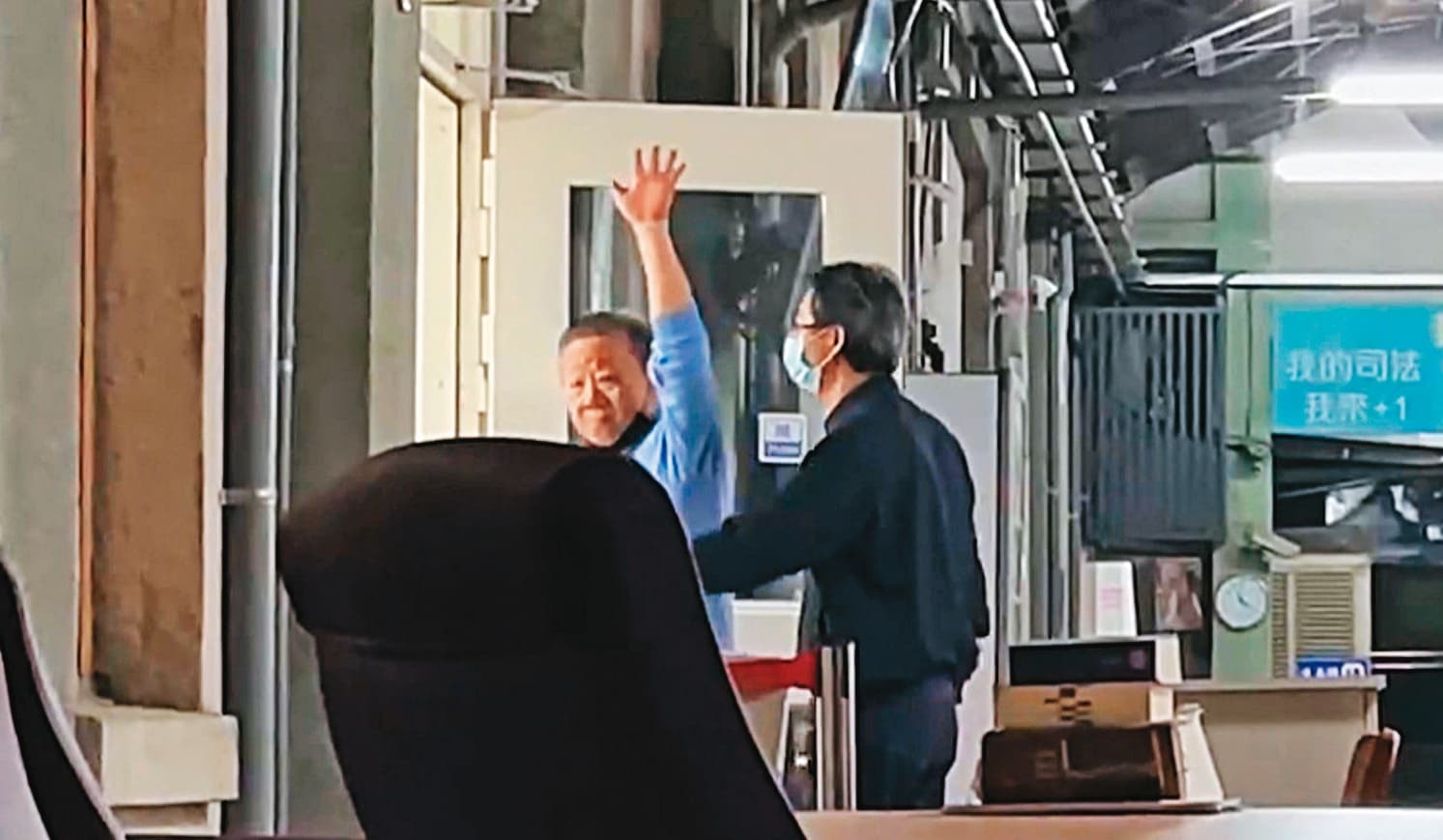 沈宗隆進入法庭審理前揮手對外示意，似乎展現對官司的信心，最後仍被法院裁押禁見。（翻攝《鏡新聞》）