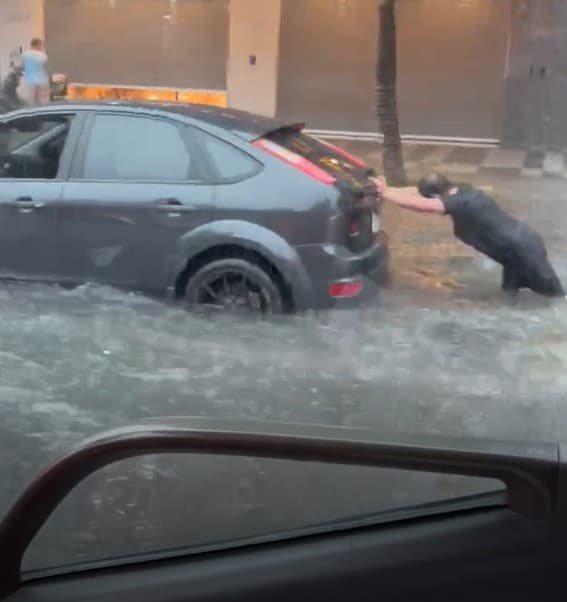 北市重慶北路積水成河，有汽機車駕駛疑似因愛車拋錨下車推行。（翻攝自記者爆料網）