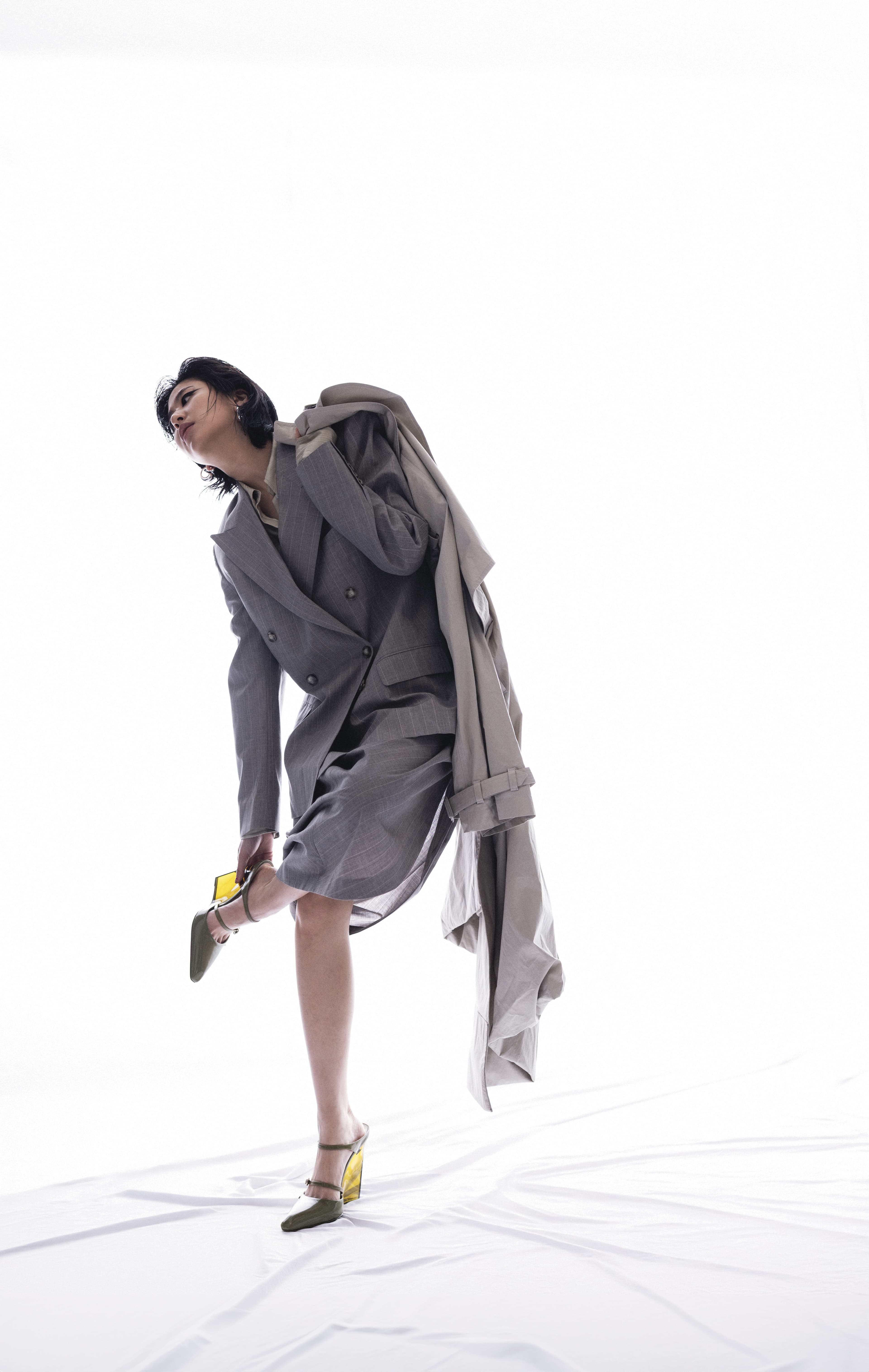 卡其色長版風衣 價格店洽 by Stella McCartney／灰色西裝外套 價格店洽 by Stella McCartney／條紋透膚襯衫 NT$52,100 by Stella McCartney／灰色過膝裙 價格店洽 by Stella McCartney ／綠色高跟鞋 價格店洽 by GUCCI／Drop純銀水滴造型耳環 價格店洽 by BOTTEGA VENETA