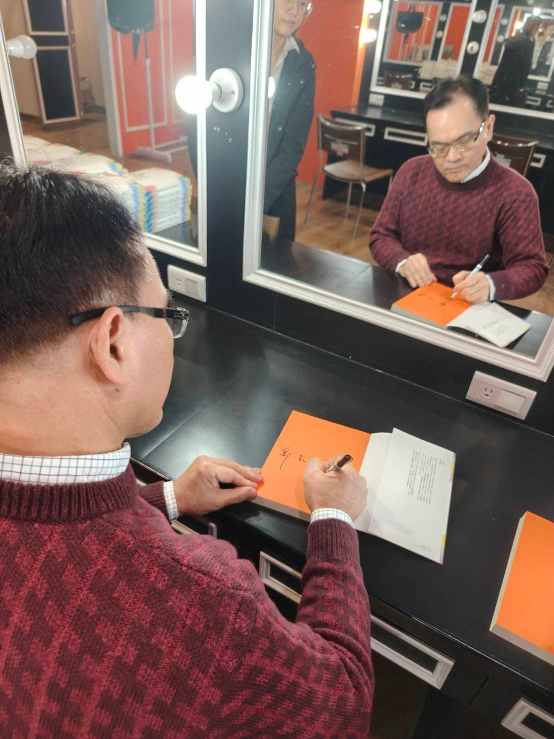 鄭弘儀在《新聞挖挖哇》後台低頭狂簽書，飯都來不及吃。（紙風車劇團提供）