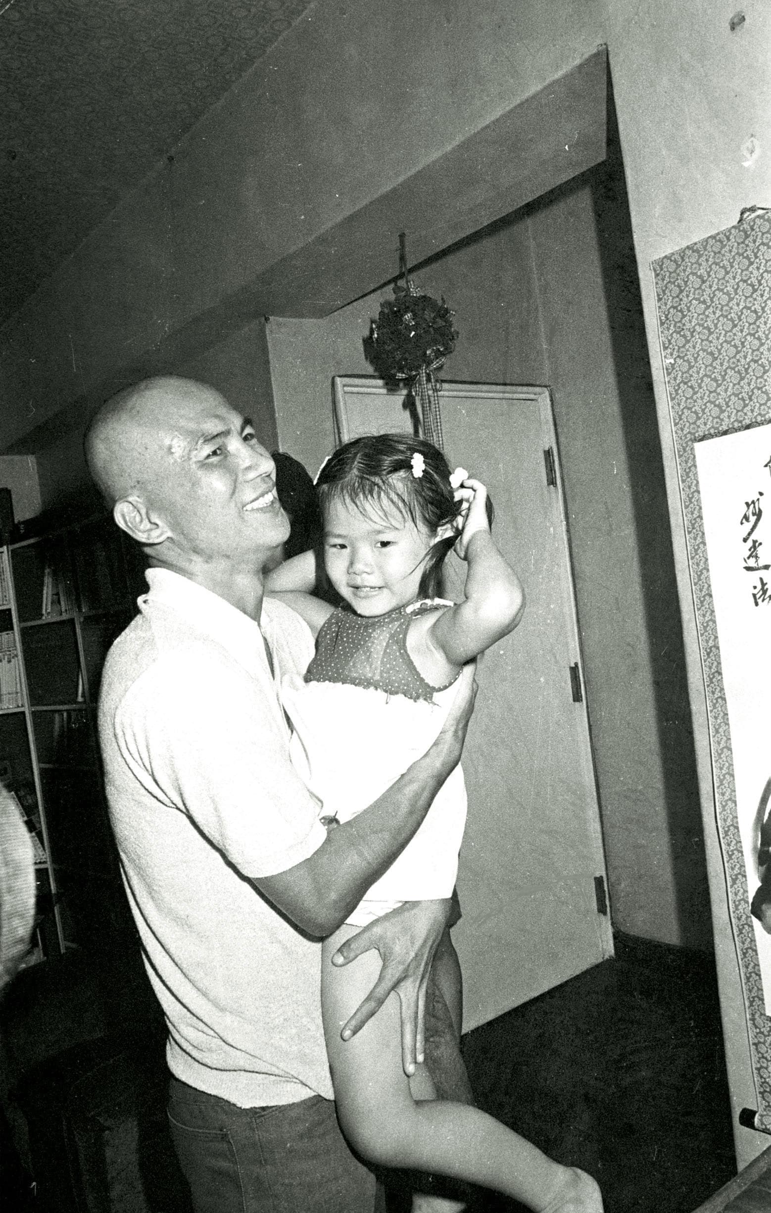 1984年，林義雄假釋返家，彼時因監所環境太差、天氣太熱，他理了個大光頭。圖為他返家後高興抱起外甥女。（中央社）